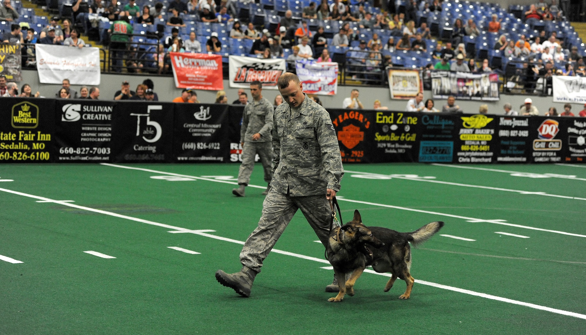 Staff Sgt. Jeffrey Besserglick, 509th SFS military working dog handler, walks his dog after performing during a demonstration for a Missouri Outlaw military appreciation game in Sedalia, Mo., April 6, 2013. The demonstration showed the capabilities of the dogs. (U.S. Air Force photo by Staff Sgt. Nick Wilson/Released)
