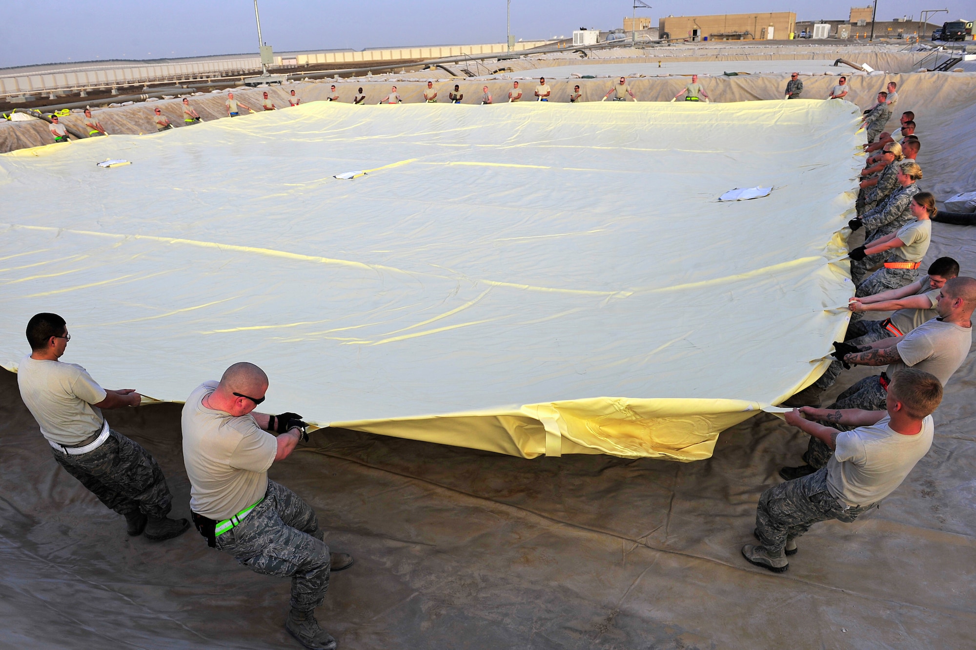Airmen assigned to the 380th Air Expeditionary Logistics Readiness Squadron arrange a 200,000 gallon fuel bladder inside a containment area at an undisclosed location in Southwest Asia April 4, 2013. Sixty Airmen operate the fuels farm, moving anywhere from 300,000 to 600,000 gallons of fuel each day. (U.S. Air Force photo by Tech. Sgt. Christina M. Styer/Released)