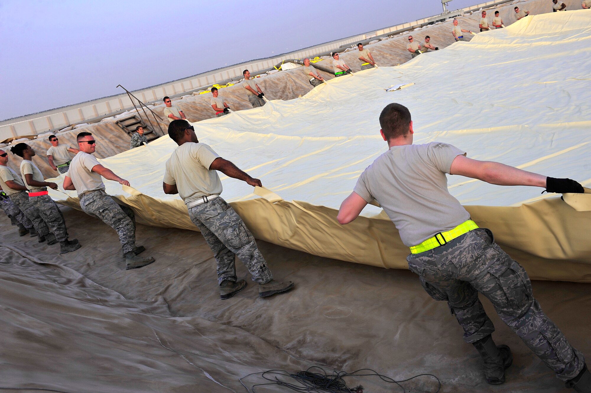 Airmen assigned to the 380th Air Expeditionary Logistics Readiness Squadron arrange a 200,000 gallon fuel bladder inside a containment area at an undisclosed location in Southwest Asia April 4, 2013. Sixty Airmen operate the fuels farm, moving anywhere from 300,000 to 600,000 gallons of fuel each day. (U.S. Air Force photo by Tech. Sgt. Christina M. Styer/Released)