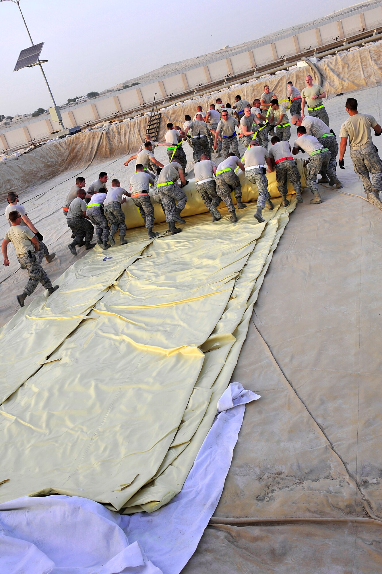 Airmen assigned to the 380th Air Expeditionary Logistics Readiness Squadron unroll a 200,000 gallon fuel bladder inside a containment area at an undisclosed location in Southwest Asia April 4, 2013. Sixty Airmen operate the fuels farm, moving anywhere from 300,000 to 600,000 gallons of fuel each day. (U.S. Air Force photo by Tech. Sgt. Christina M. Styer/Released)