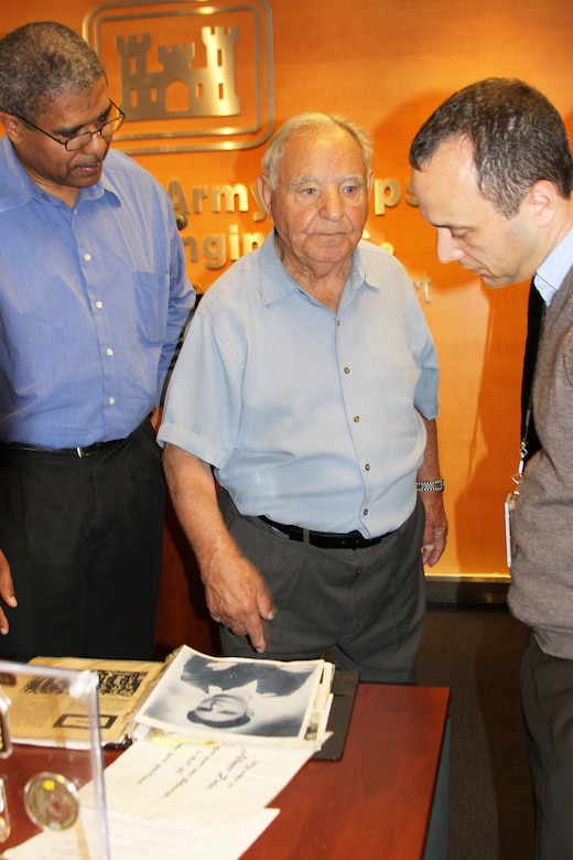 Holocaust survivor Albert Rosa shows employees his photos and other items he brought for his visit to talk about his experience in the concentration camps April 9. 