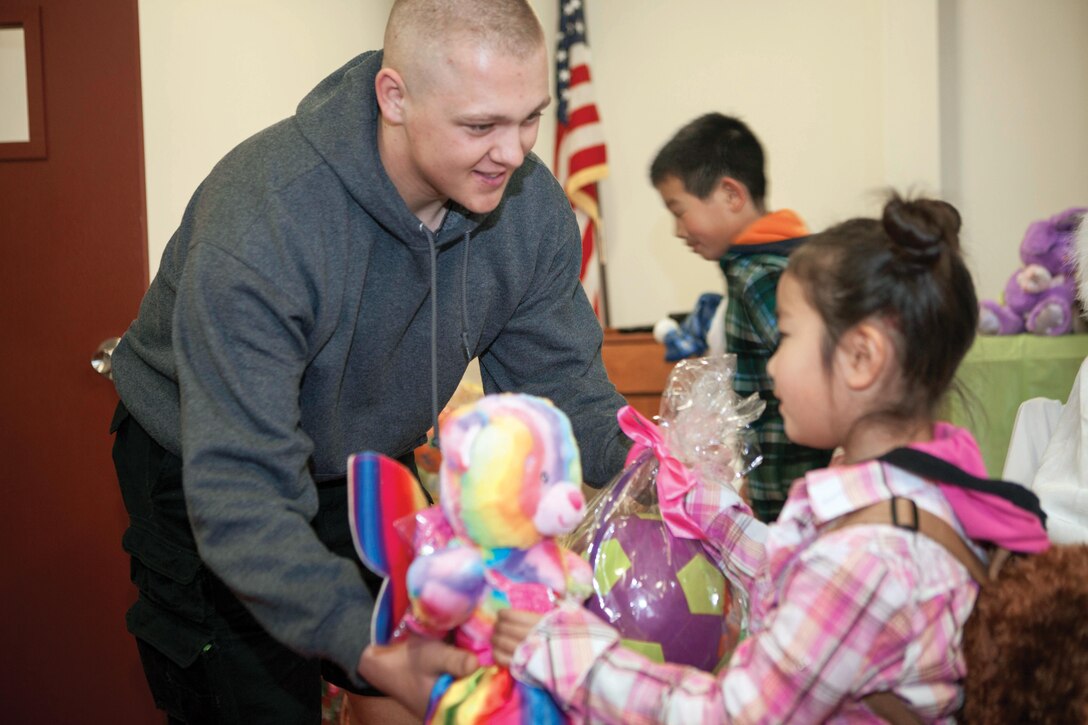 Pfc. George Von Toman presents an Easter basket and stuffed animal March 30 during an annual festival celebrating both Easter and spring at Combined Arms Training Center Camp Fuji, Japan. The event brought children from three nearby orphanages to the camp to participate in Easter activities such as egg-painting, an egg hunt and relay races. Von Toman is a food service specialist with Headquarters Company, CATC Camp Fuji. Photo by Cpl. Adam B. Miller