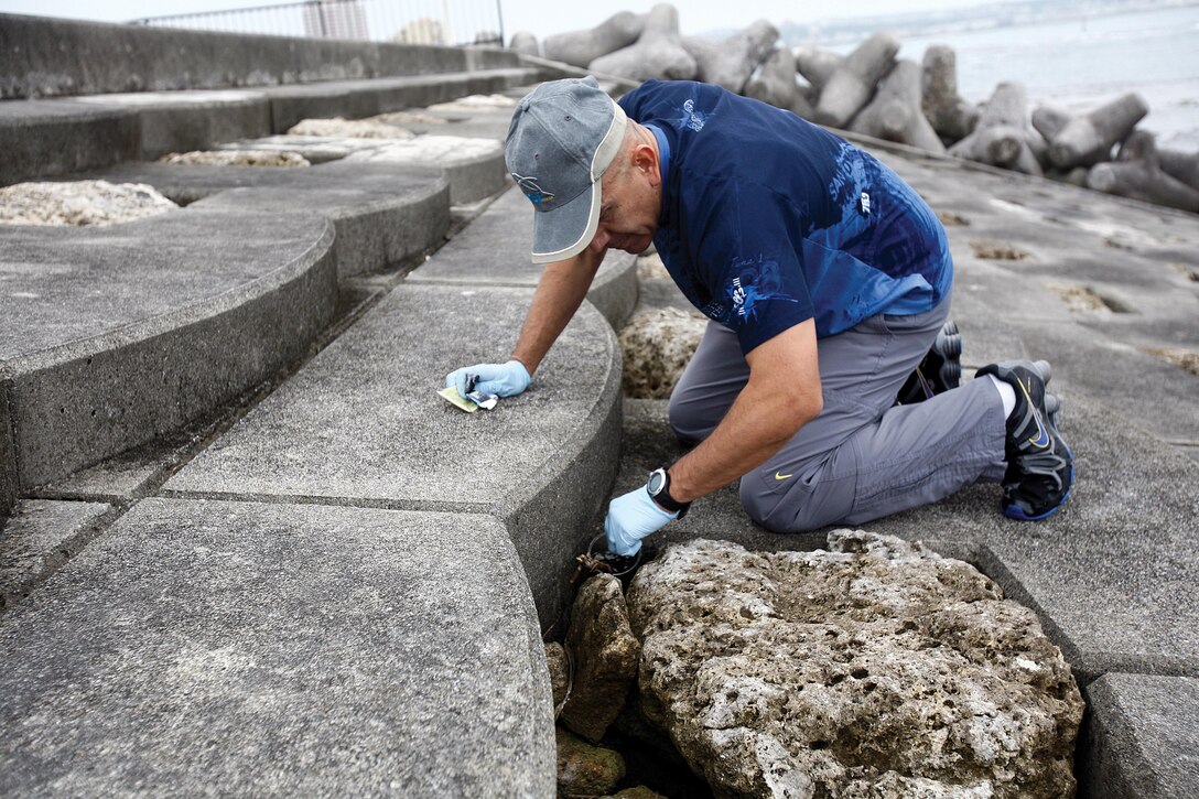 Master Gunnery Sgt. Pete De La Rosa collects litter during a seawall cleanup April 10 in Chatan Town. The cleanup was a part of Tomo Days, which was initiated to highlight the relationship between the Japanese community and military personnel following the 2nd anniversary of the Great East Japan Earthquake and subsequent tsunami. De La Rosa is the camp services chief for Headquarters and Service Battalion, Marine Corps Base Camp Smedley D. Butler. Photo by Lance Cpl. Nicholas S. Ranum