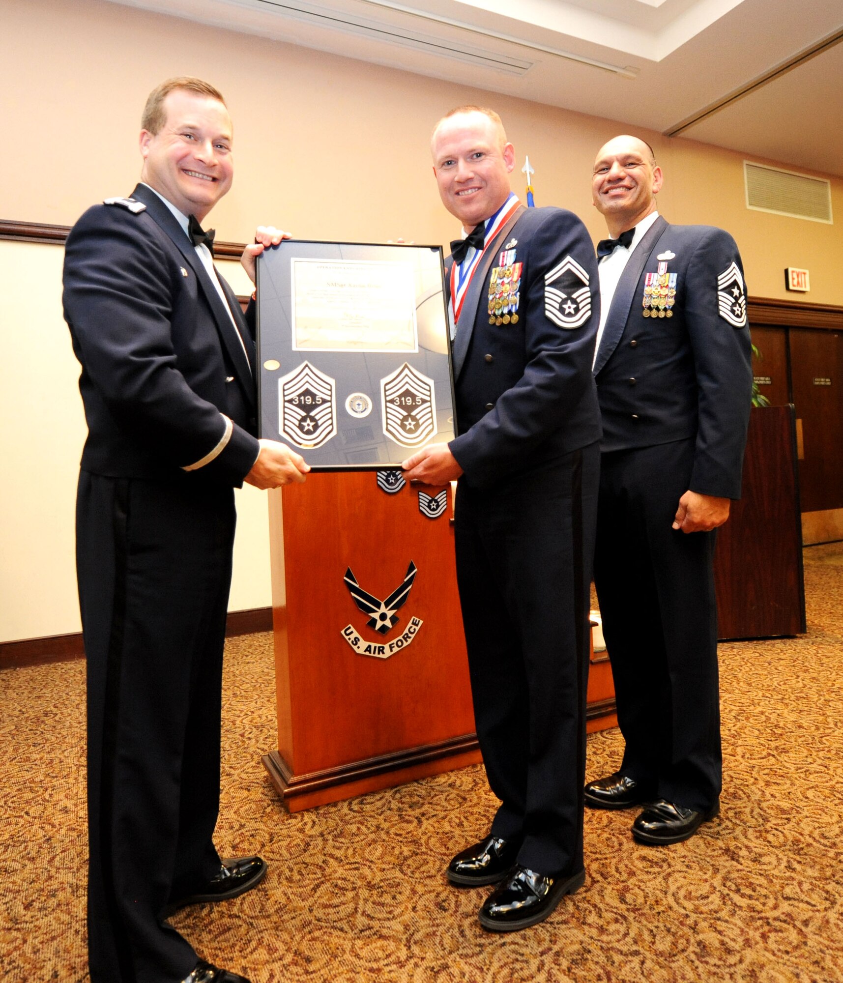Col. Phil Stewart (left), 9th Reconnaissance Wing commander, and Chief Master Sgt. Robert White, 9th Reconnaissance Wing command chief, present Chief Master Sgt. Aaron Renn, 99th Aircraft Maintenance Unit superintendant, a plaque commemorating his promotion at the Recce Point Club on Beale Air Force Base, Calif., April 8, 2013. (U.S. Air Force photo by Airman 1st Class Bobby Cummings/Released)