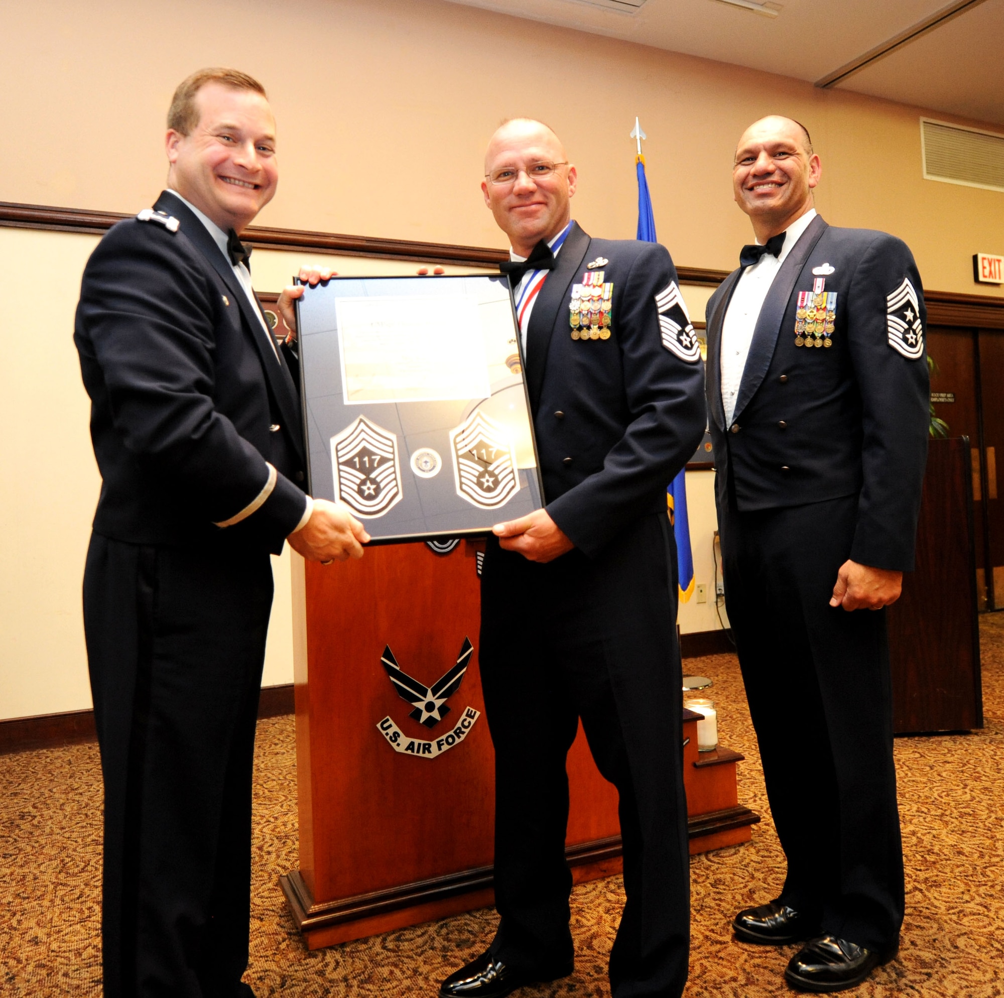 Col. Phil Stewart (left), 9th Reconnaissance Wing commander, and Chief Master Sgt. Robert White, 9th Reconnaissance Wing command chief, present Chief Master Sgt. Thomas Jenkins, 12th Aircraft Maintenance Unit superintendant, a plaque commemorating his promotion at the Recce Point Club on Beale Air Force Base, Calif., April 8, 2013. (U.S. Air Force photo by Airman 1st Class Bobby Cummings/Released)