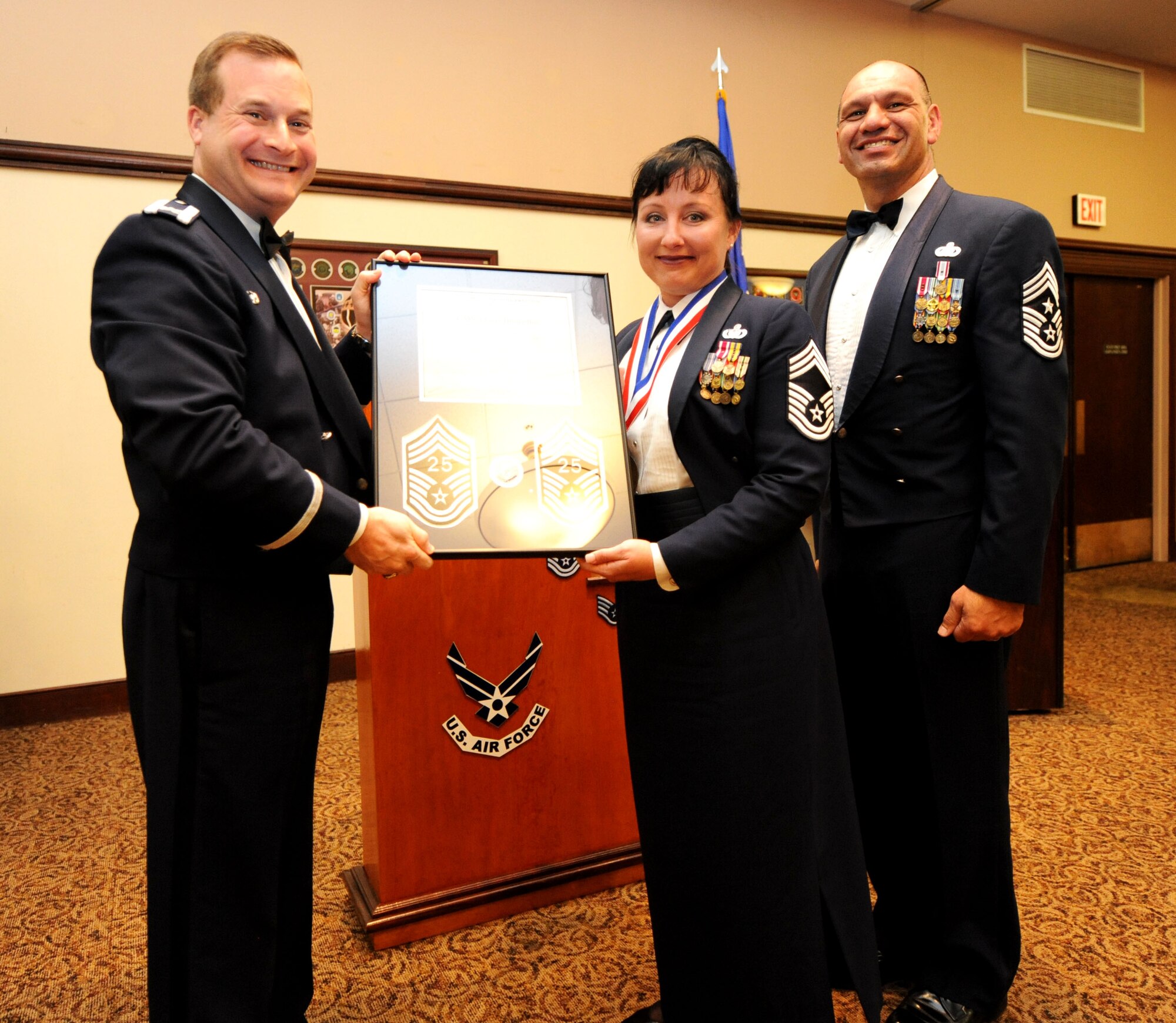 Col. Phil Stewart (left), 9th Reconnaissance Wing commander, and Chief Master Sgt. Robert White, 9th Reconnaissance Wing command chief, present Chief Master Sgt. Geri Dreibelbis, 9th Security Forces Squadron security forces manager, a plaque commemorating her promotion at the Recce Point Club on Beale Air Force Base, Calif., April 8, 2013. (U.S. Air Force photo by Airman 1st Class Bobby Cummings/Released)