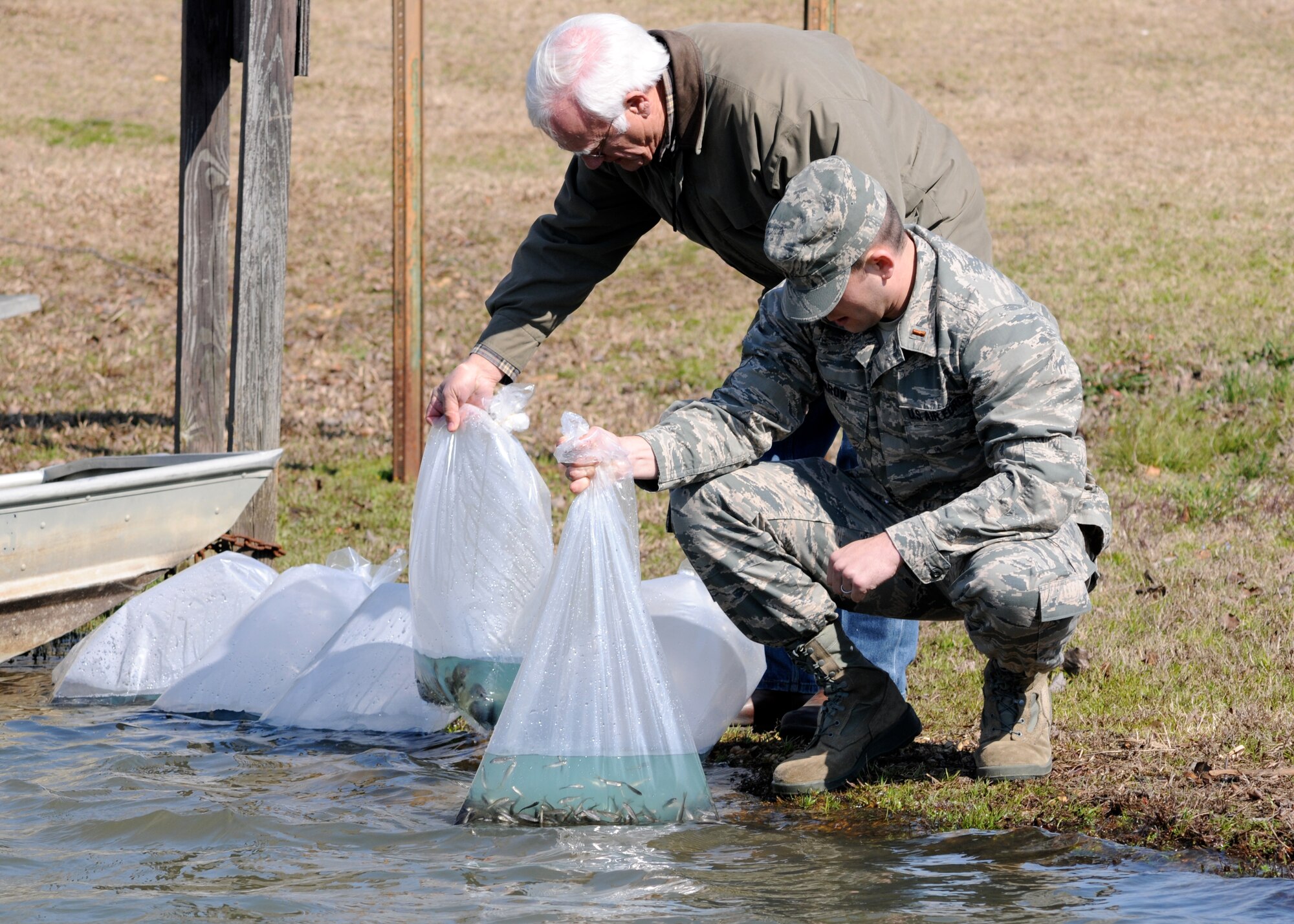 Frank Lockhart, 14th Civil Engineer Squadron Conservation Manager and 2nd Lt. Jeffrey Morrow acclimate fingerling fish to the water in SAC Lake on Columbus Air Force Base. After these 300 fingerlings are released, they will grow larger to be one day fished for outdoor recreation. The fingerlings were purchased with funds generated from fishing permits.  (U.S. Air Force Photo)