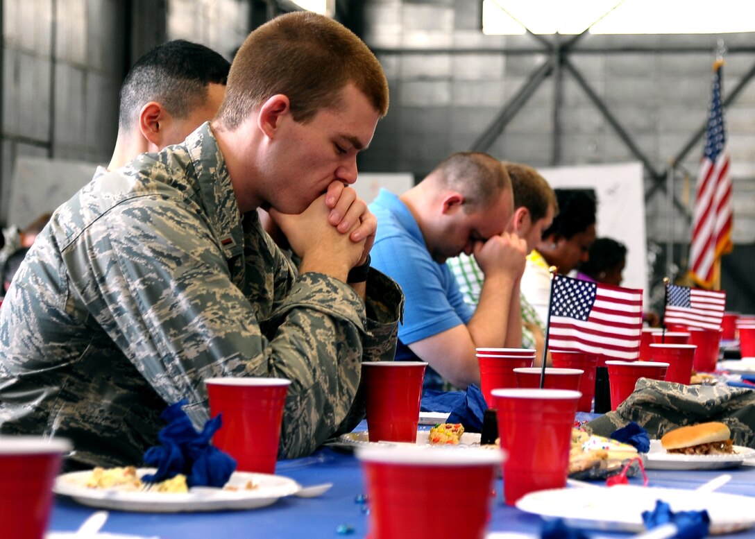 Airmen and civilians bow their heads in silence during a prayer conducted by Maj. Leslie Janovec, 14th Flying Training Wing Chaplain, on April 9th at the National Prayer Picnic held in Hangar 3 on Columbus Air Force Base. The picnic was put together by members of the base chapel and included songs and prayers to accompany the lunchtime meal. (U.S. Air Force Photo/Airman 1st Class Stephanie Englar)