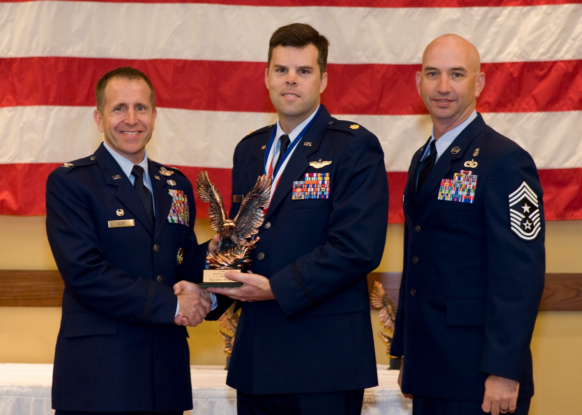 Col. Jim Slife, commander of 1st Special Operations Wing, left, and Chief Master Sgt. Jeff Maberry, command chief of 1st SOW, right, present Maj. James Womble, Battle Staff director of 1st SOW, center, with the 1st SOW Field Grade Officer of the Year award at the 2012 1st SOW Annual Awards Luncheon at the Soundside Club at Hurlburt Field, Fla., April 11, 2013. (U.S. Air Force photo by Airman 1st Class Christopher Callaway)