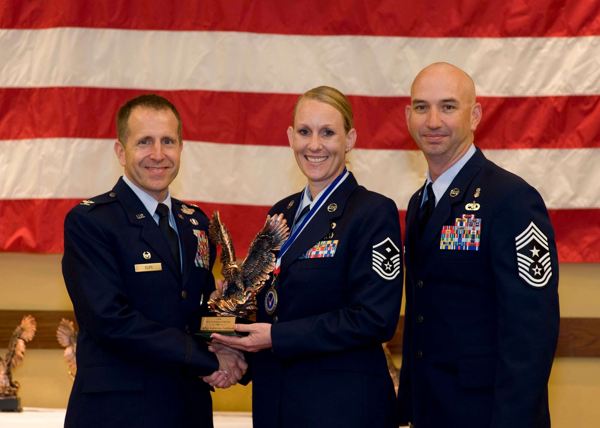 Col. Jim Slife, commander of 1st Special Operations Wing, left, and Chief Master Sgt. Jeff Maberry, command chief of 1st SOW, right, present Master Sgt. Katherine Grabham, first sergeant of 1st Special Operations Maintenance Squadron, center, with the 1st SOW First Sergeant of the Year award at the 2012 1st SOW Annual Awards Luncheon at the Soundside Club at Hurlburt Field, Fla., April 11, 2013. (U.S. Air Force photo by Airman 1st Class Christopher Callaway)