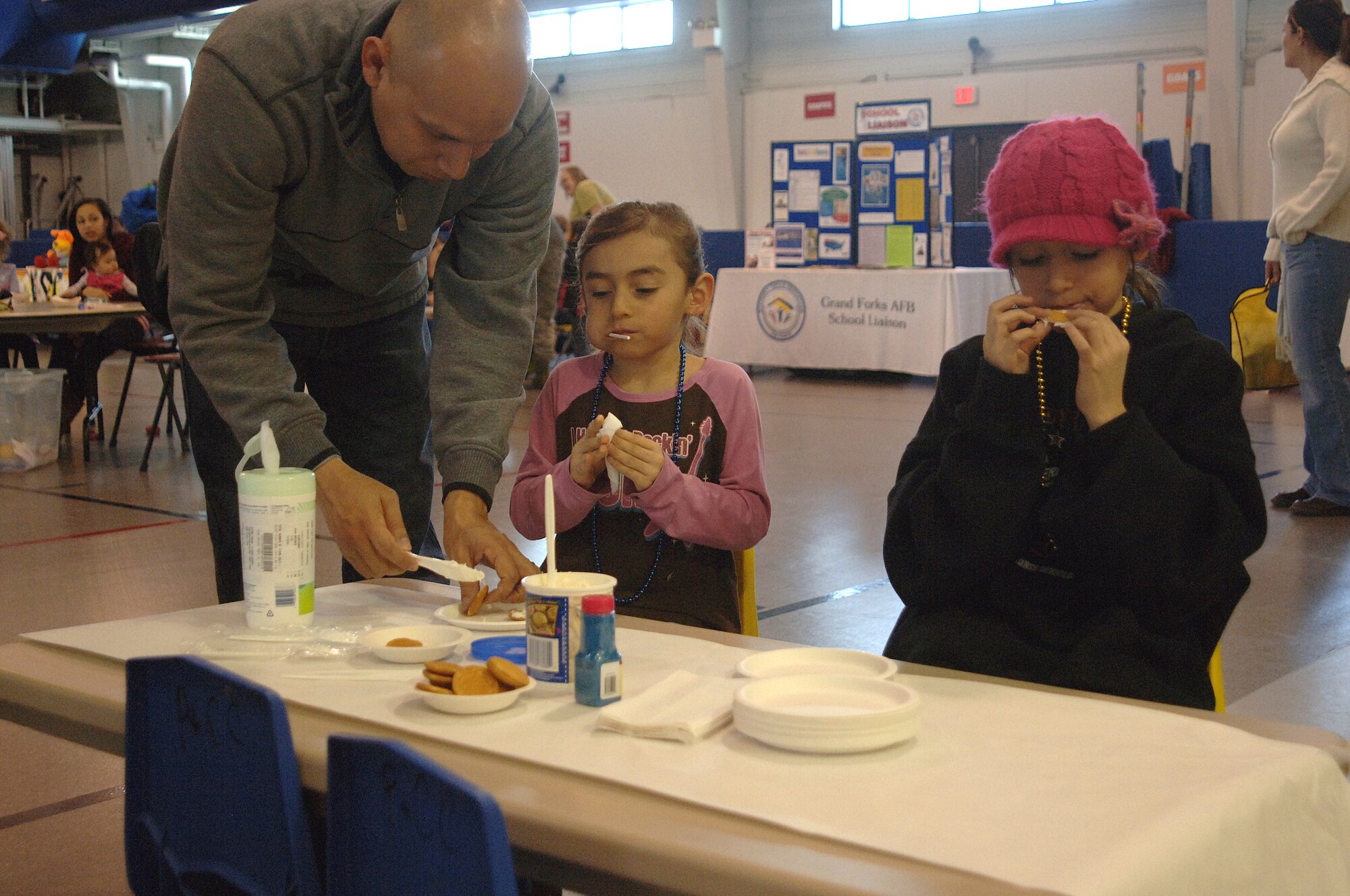 Miranda Salcedo, center, coats her cookie with icing while her sister, Marissa Salcedo, snacks during the Beautiful Child Photo Shoot and Activity Fair held April 9, 2013, at Liberty Square on Grand Forks Air Force Base, N.D. Booths at the event offered children the opportunity to learn and interact with others through hands-on activities. (U.S. Air Force photo/ Airman 1st Class Zachiah Roberson)