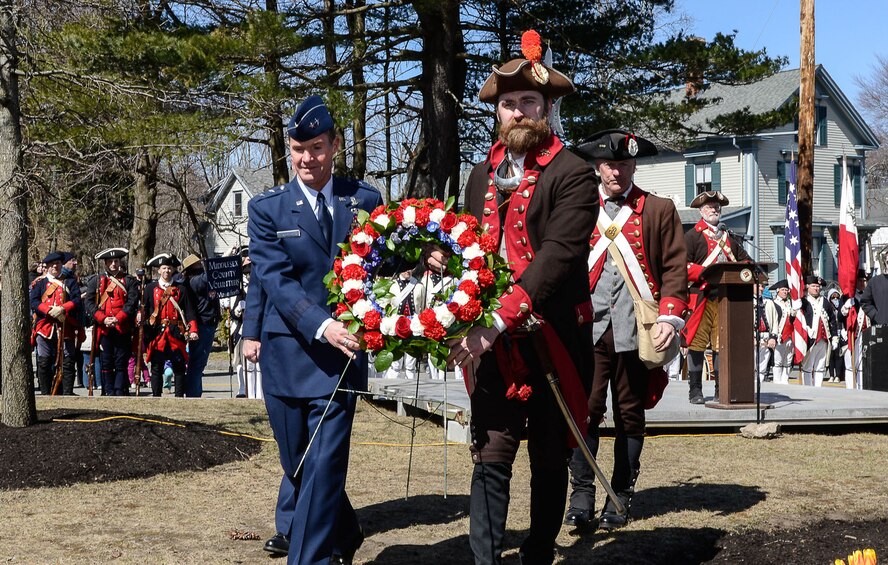 BEDFORD, Mass. – Maj. Gen. Craig S. Olson (left), C3I&N program executive officer, helps a Revolutionary War reenactor place a wreath at Wilson Park, the site where Bedford Minuteman gathered before marching to Concord April 19, 1775, at the start of the Revolutionary War. The wreath laying was part of the town of Bedford’s annual Pole Capping event April 7. (U.S. Air Force photo by Walter Santos)