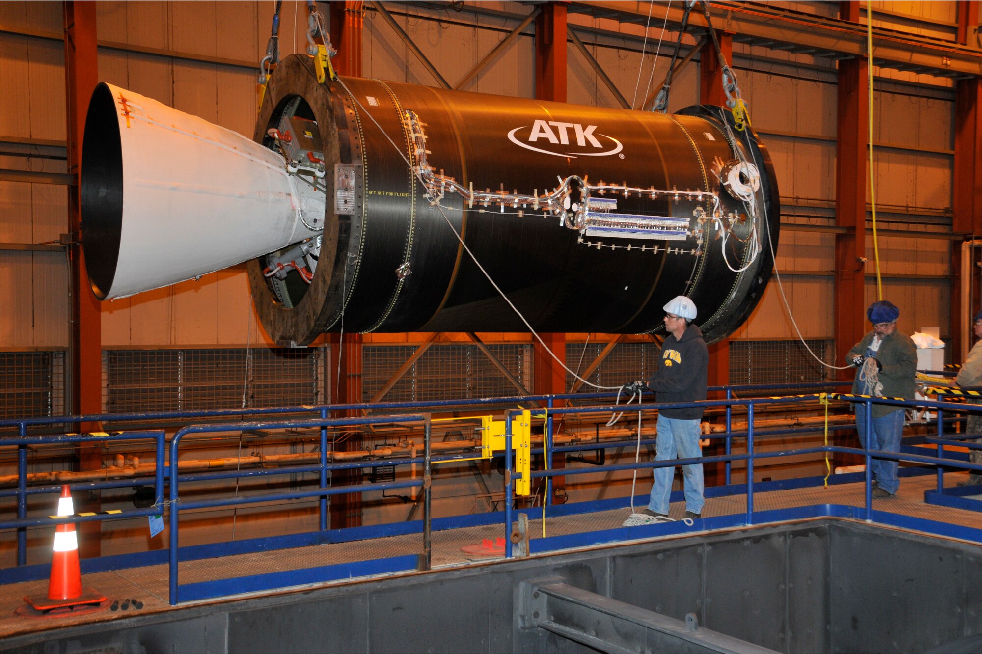 From left, AEDC’s Mike Mills, an outside machinist, David Amonette, a boilermaker, and Barry Long, an electrician, position the ATK CASTOR® 30XL rocket motor into place for simulated altitude static testing at AEDC’s J-6 Large Rocket Motor Testing facility. (Photo by Rick Goodfriend)
