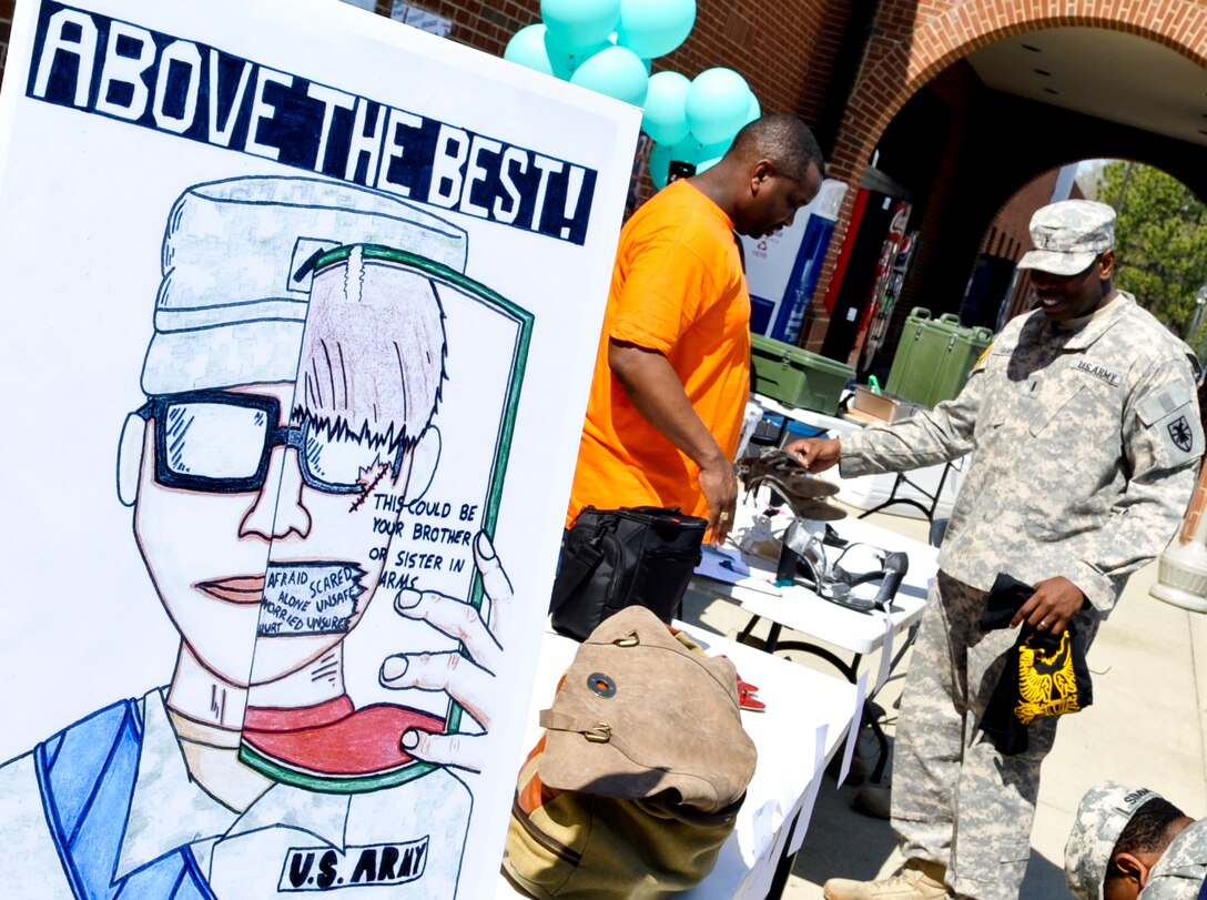 A Soldier checks out a pair of women’s shoes at the registration table for the Walk a Mile in Her Shoes event held at Fort Eustis, Va., April 10, 2013. The wearing of women’s shoes by men signifies the old saying “to walk a mile in their shoes is to understand their perspective on life”. (U.S. Air Force photo by Staff Sgt. Wesley Farnsworth/Released)
