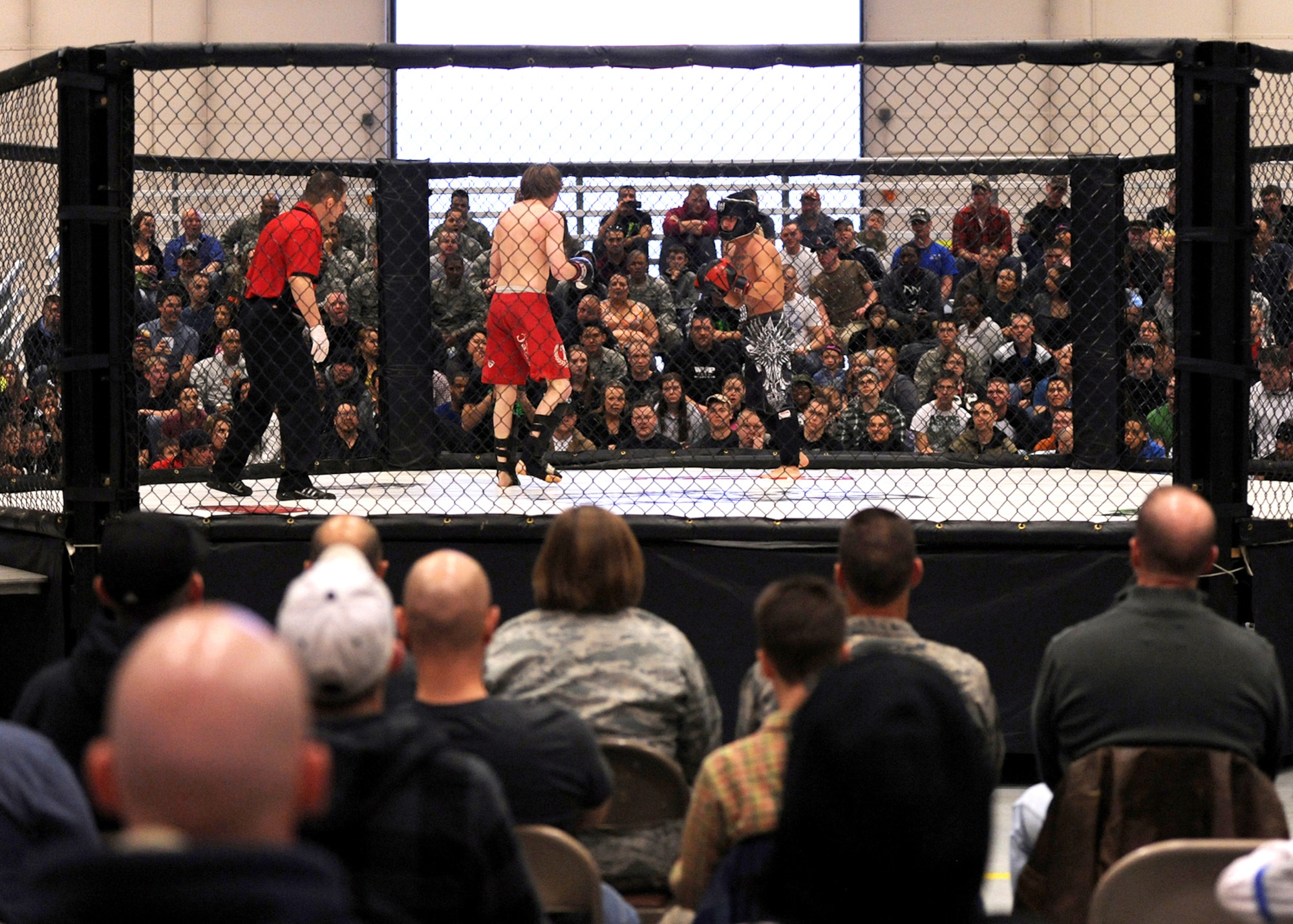 Two kickboxers circle around one another as referee, Bret Hamlin, looks on during 221 Industries’ first-ever Fight For the Troops event at Malmstrom Air Force Base, Mont., on April 5. More than 1,100 Team Malmstrom members attended the event. (U.S. Air Force photo/Staff Sgt. R.J. Biermann)