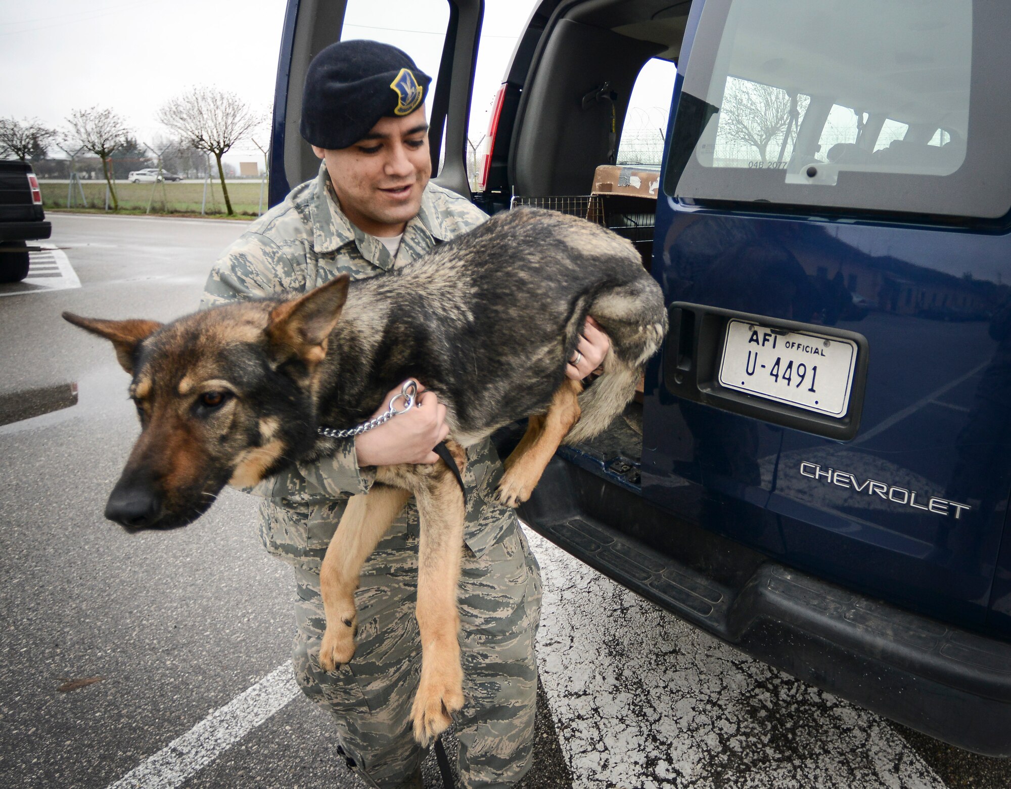 Staff Sgt. Manuel Gamboa, 31st Security Forces Squadron military working dog trainer, carries Soma, 31st SFS explosives detection dog, during a visit to the base’s veterinary clinic for a post-operation check up March 29. Soma recently underwent surgery for a compressed spinal disk, a common malady in large dog breeds and is on the road to recovery. (U.S. Air Force photo/Senior Airman Katherine Tereyama)