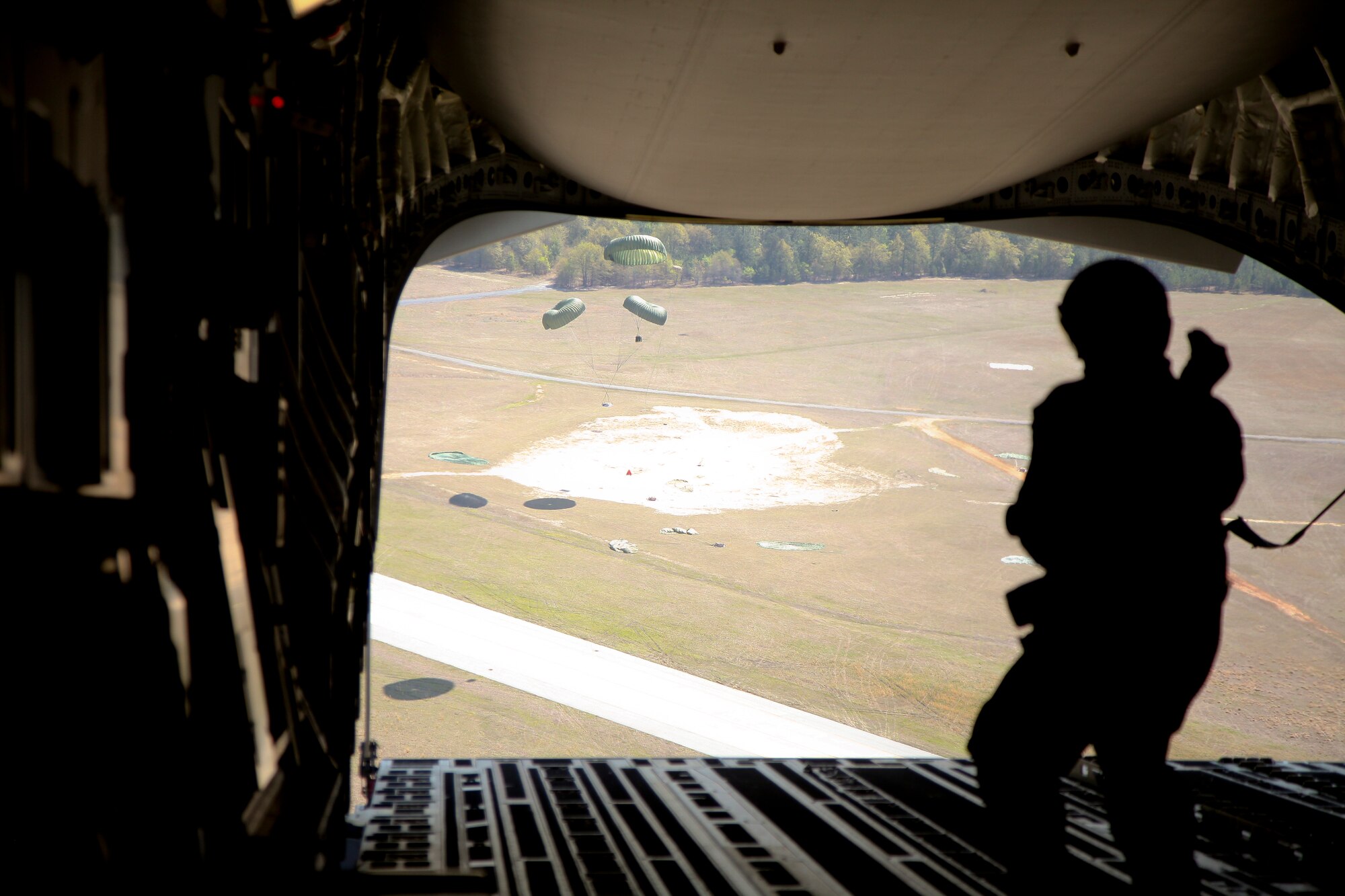 Staff Sgt. James Richardson, a combat camera operator with the 1st Combat Camera Squadron at Joint Base Charleston, S.C., watches a cargo load parachute to the ground today after it was dropped from the cargo bay of a C-17 Globemaster III during a training mission. The mission, named Exercise Furious Moose, was a joint total-force effort between JB Charleston’s active duty airmen of 437th Airlift Wing and the Reserve airmen of the 315th Airlift Wing, which included completing a variety of mission readiness training objectives for aircrews, maintenance and support crews. (U.S. Air Force photo by Staff Sgt. Rashard Coaxum/released)