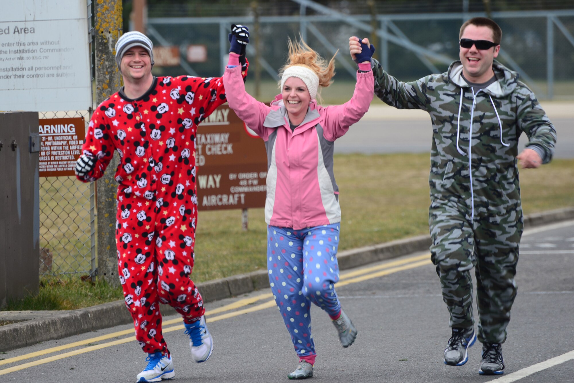 ROYAL AIR FORCE LAKENHEATH, England -- Staff Sgt. Shane Baze (right), 48th Civil Engineering Squadron explosive ordnance disposal technician, wife Sariah Baze (middle) and Senior Airman Corbin Stewart (left), 48th CES EOD technician,  cross the finish line together during  RAF Lakenheath's 3rd Annual Phil Myers Memorial 5K April 4, 2013. One hundred percent of the donations from the run went to the EOD Warrior Foundation and the Wounded Warrior Project. (U.S. Air Force photo by Airman 1st Class Dana J. Butler)