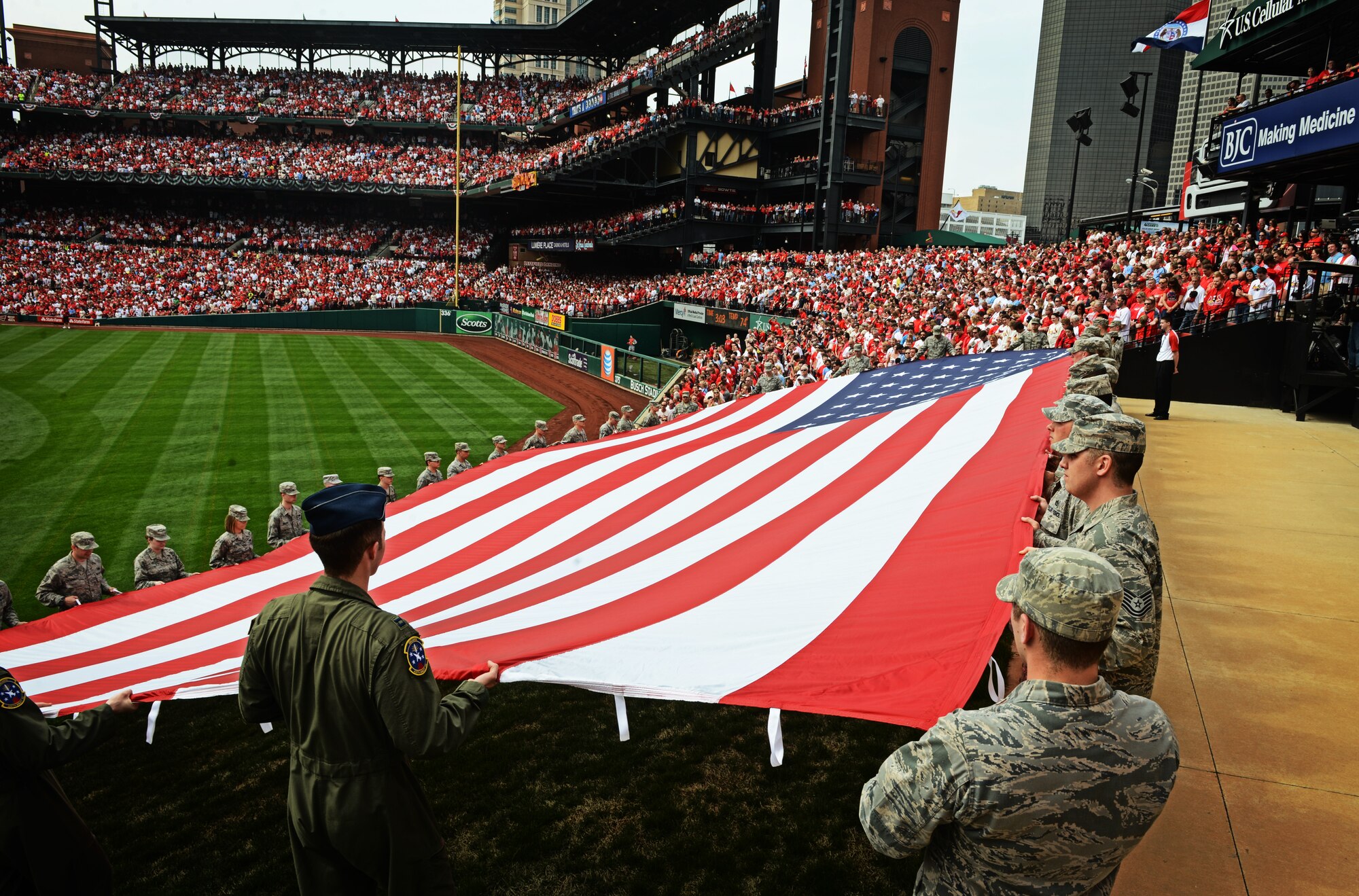 Airmen from the 375th Air Mobility Wing, Scott Air Force Base, Ill., present the giant American flag for nearly 50,000 fans to see at Busch Stadium, home of the St. Louis Cardinals, April 8, 2013. Scott AFB has been involved in numerous community sporting events, but this was the first time they presented the flag at the opening day of the season. The Cardinals went on to lose to the Cincinnati Reds 13-4. (U.S. Air Force photo/ Staff Sgt. Ryan Crane)