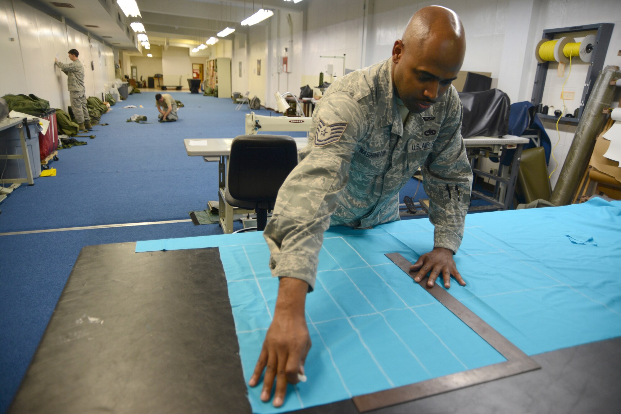 U.S. Air Force Tech Sgt. Roy Washington, 18th Operation Support Squadron NCOIC of air crew flight equipment, measures fabric to be cut and sewn into flags for Sexual Assault Awareness Month, March 13, 2013, Kadena Air Base, Japan.  The flags are going to be available by donation at various places around the base and will be planted in the shape of a ribbon on Douglas Blvd. to honor survivors of sexual assault. (U.S. Air Force Photo/Tech Sgt. Jocelyn L. Rich-Pendracki)