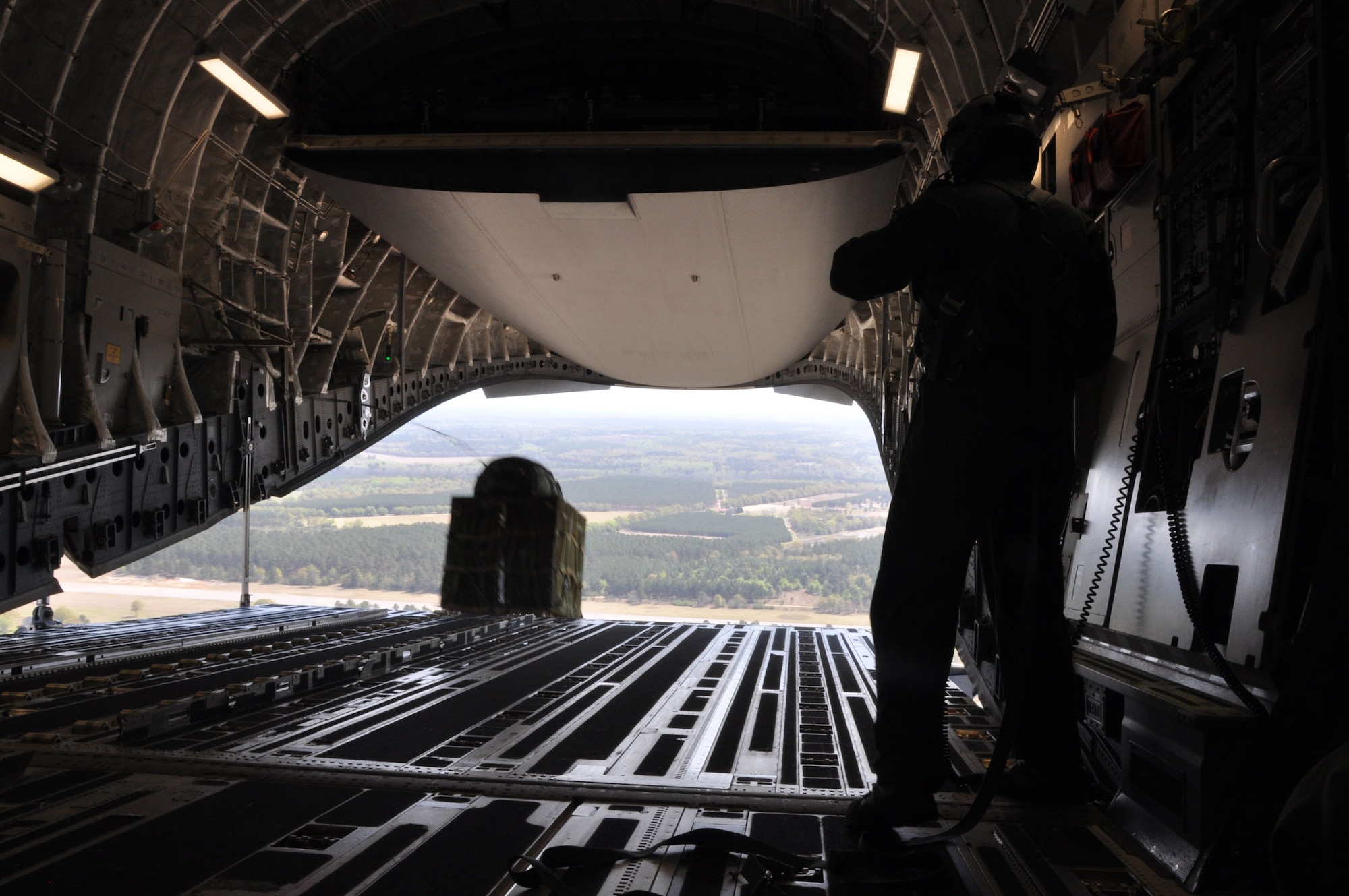 Tech. Sgt. Mark R. Corrigan, a loadmaster assigned to the 317th Airlift Squadron at Joint Base Charleston, S.C., monitors cargo exiting a C-17 Globemaster III aircraft during a recent training mission over North Auxiliary Airfield, North, S.C.  Aircrews from the 437th and 315th Airlift Wings at Joint Base Charleston conducted a large formation exercise (LFE) consisting of 13 C-17 Globemaster III aircraft Wednesday, April 9, 2013.  The mission included a variety of training exercises consisting of airdrops, aerial refueling and low level tactical training. These skills are needed at all times to ensure mission readiness, locally and globally. (U.S. Air Force photo/Senior Airman Bobby Pilch)