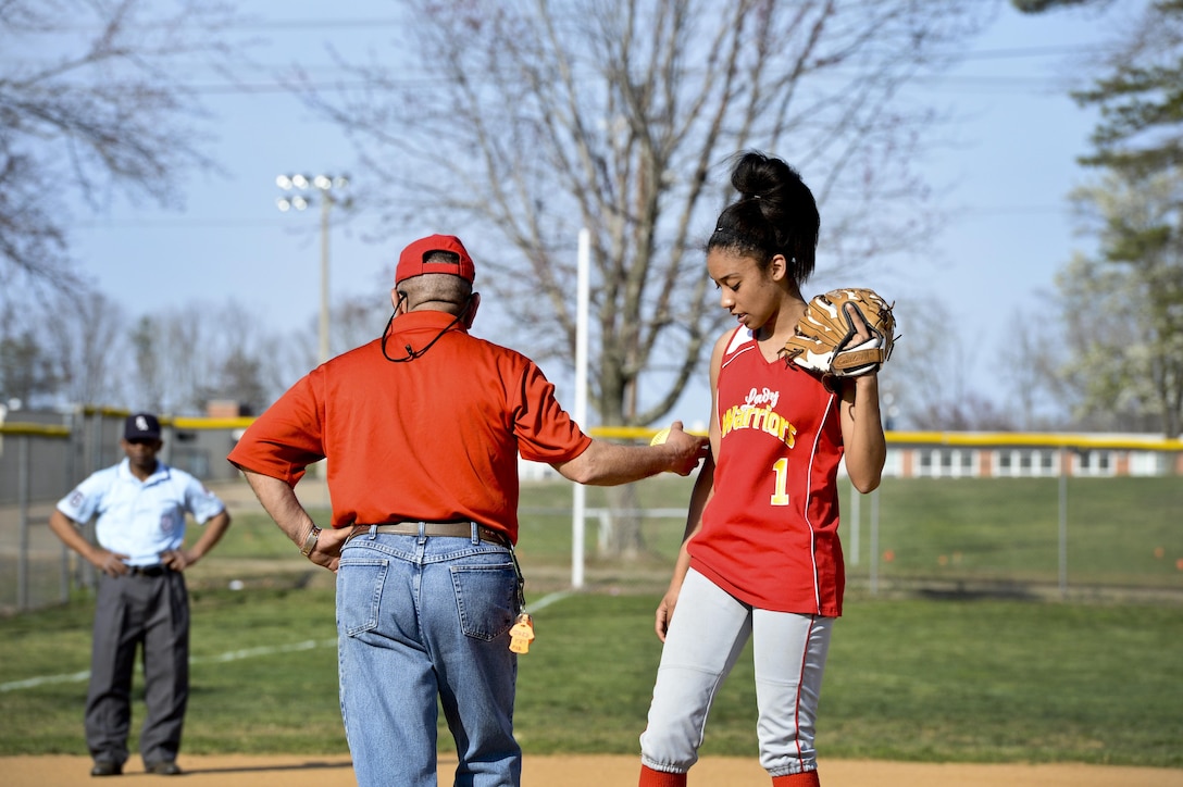 Jose Diaz, Quantico Lady Warrior’s coach, gives Marquis, Lady Warrior’s pitcher, a reassuring nudge after a pep talk during a softball game against Maryland School for the Deaf’s Orioles at Quantico on April 9, 2013. Marquis struggled in the fourth inning against the Oriole’s heavy bats and allowed 10 runs.