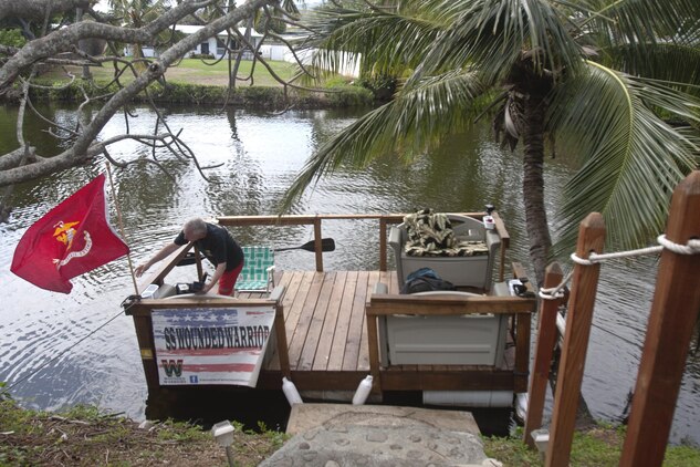 KAILUA, Hawaii - Steve Jensen, a Navy veteran and Wounded Warrior volunteer chaplain, hangs a Marine Corps flag on a barge, April 2.(U.S. Marine Corps photo by Lance Cpl. Janelle Y. Chapman) 