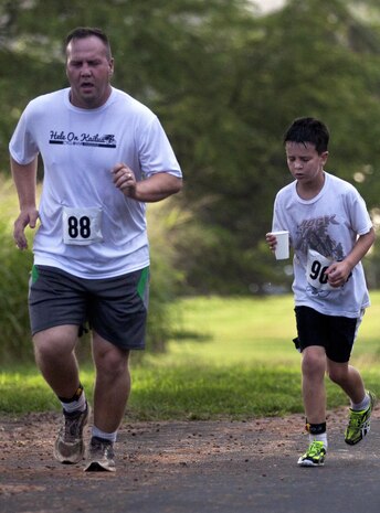 MARINE CORPS BASE HAWAII - Master Sgt. Daniel Palumbo, of Largo, Fla., who works with 647th Security Forces in Joint Base Pearl Harbor-Hickam, runs next to his son in the Surf and Turf 5K race, April 6. (U.S. Marine Corps photo by Lance Cpl. Matthew Bragg)