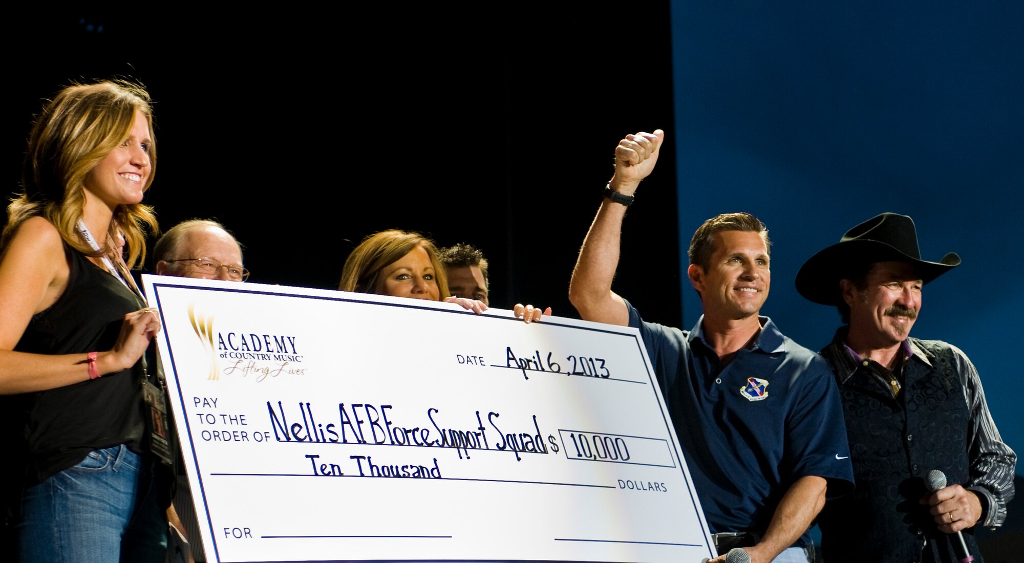Col. Barry Cornish, 99th Air Base Wing commander, accepts a check for the Nellis Air Force Base Force Support Squadron at the Academy of Country Music Party for a Cause festival April 6, 2013, at the Orleans Hotel and Casino in Las Vegas. The money was donated by the Academy of Country Music Lifting Lives. Lifting Lives is the charitable arm of the Academy of Country Music dedicated to improving lives through the power of music.  The check is going to be used for Nellis and Creech AFB youth programs. (U.S. Air Force Photo by Airman 1st Class Jason Couillard)