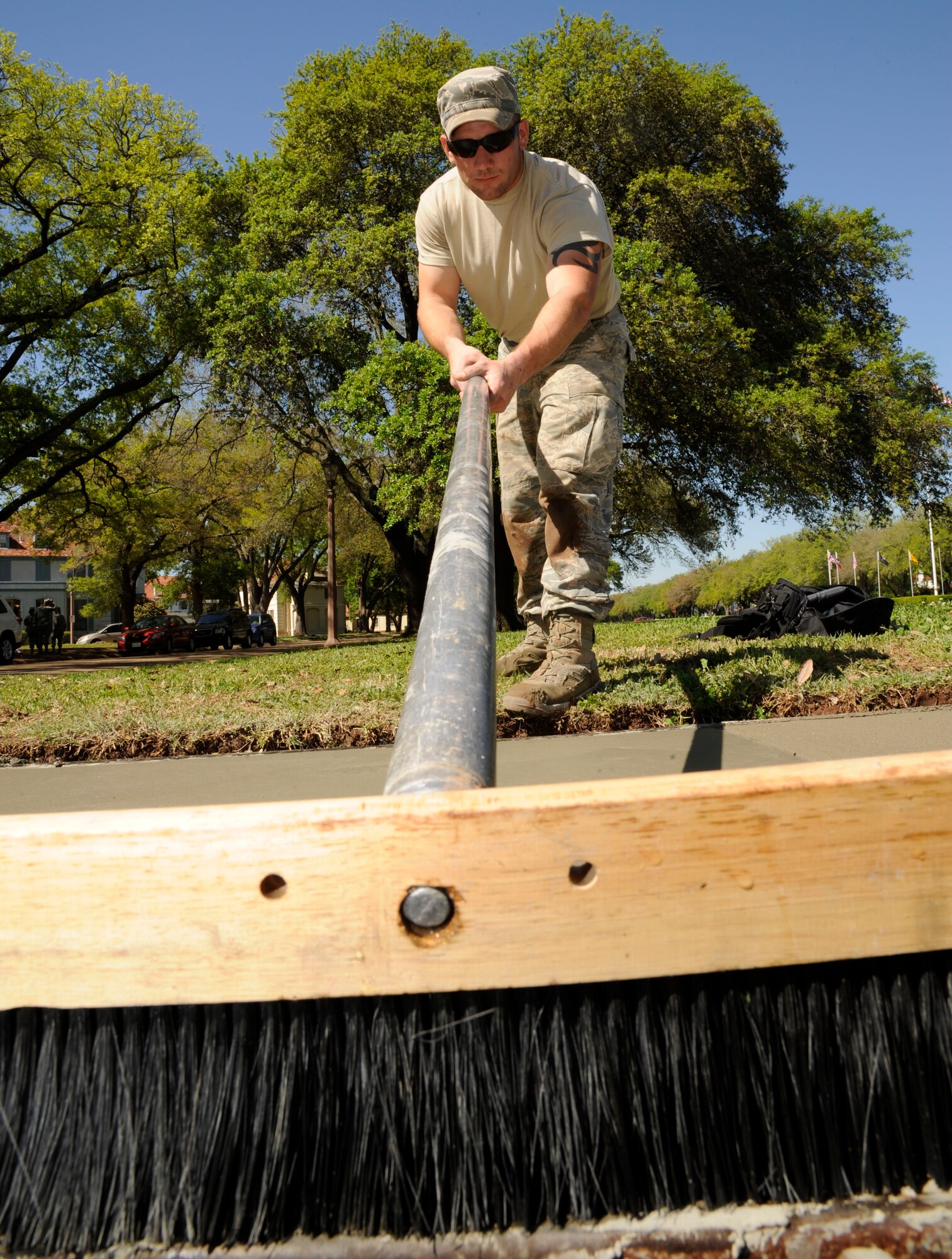 Airman 1st Class Ali Trincado, uses a broom on a freshly laid sidewalk on Barksdale Air Force Base, La., April 12, 2013. Trincado used the broom to create a non-slip surface on the sidewalk. (U.S. Air Force photo/Airman 1st Class Andrew Moua)