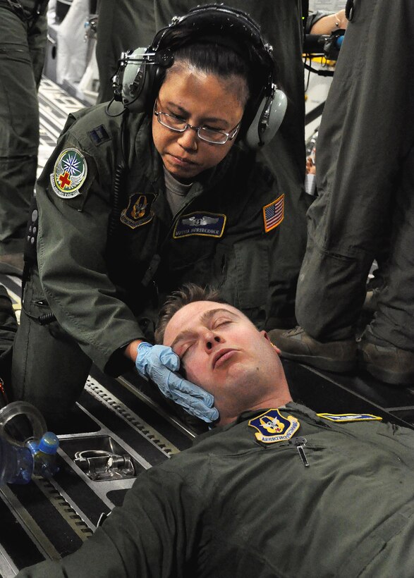 Capt. Mutita Hornsberger, 446th Aeromedical Evacuation flight nurse, supports Capt. Steven Smith, 446th AES flight nurse, as he "vomits blood" during a C-17 training exercise April 7. Hornsberger, along with other Reservists, is being evaluated on her ability to respond to different in-flight medical scenarios. Flight nurses and medical technicians are required to fly on a training mission every 60 to 90 days to stay current on their training requirements. (U.S. Air Force Photo/Airman 1st Class Madelyn McCullough)