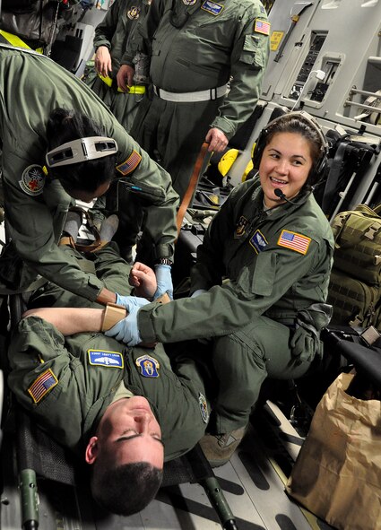 Tech Sgt. Darlena Martens (right), 446th Aeromedical Evacuation Squadron medical technician, and Capt. Jana Sanders (left), 446th AES flight nurse, work to tie Master Sgt. Larry Jones, 446th AES medical technician, to a litter during a C-17 training exercise April 7. Jones was pretending to be a psychiatric patient who snuck into the narcotics and overdosed. (U.S. Air Force Photo/Airman 1st Class Madelyn McCullough)