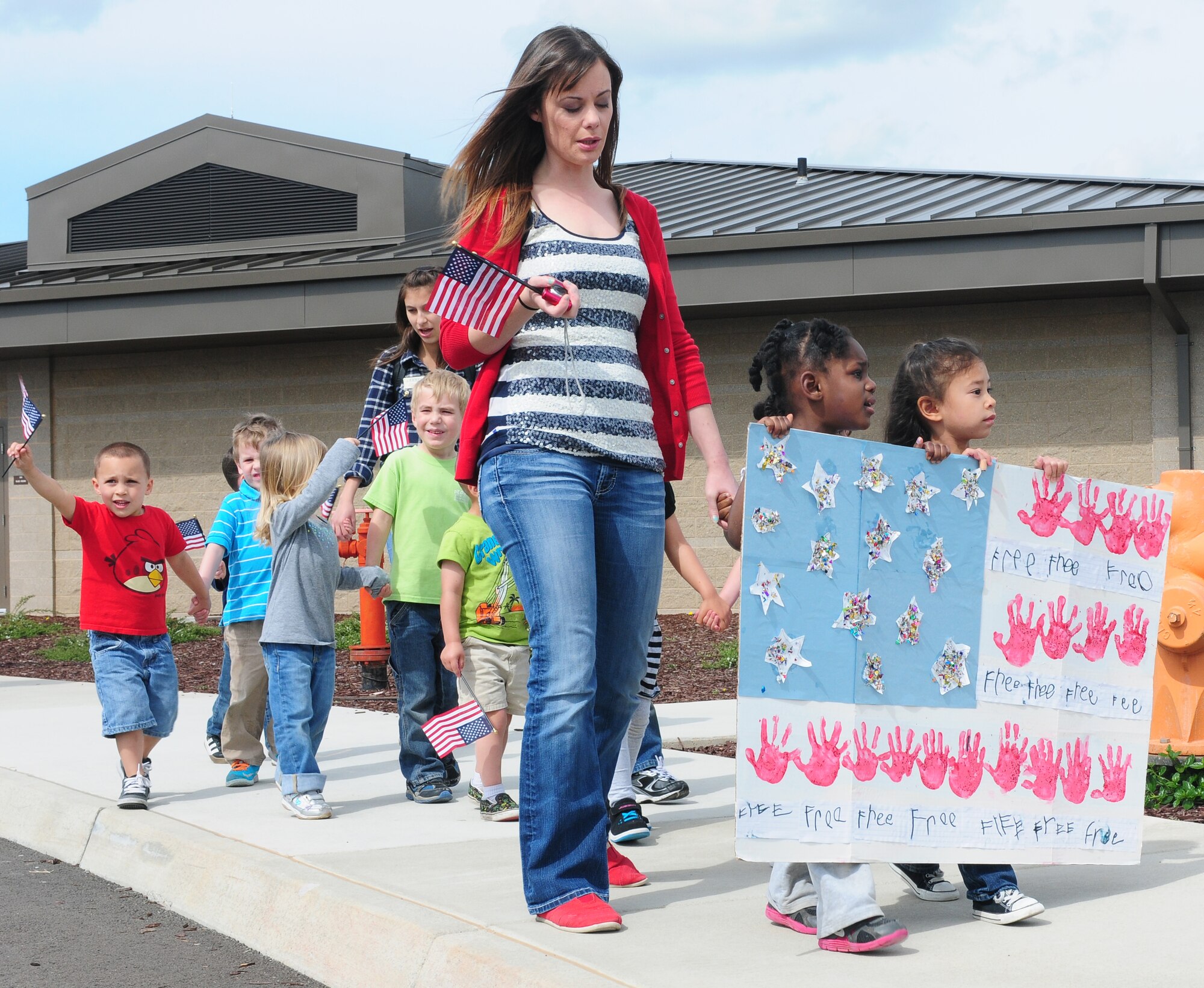 Staff and children of the Child Development Center participate in a parade celebrating the month of the military child at Beale Air Force Base Calif., April 5, 2013. The children paraded the sidewalk surrounding the CDC carrying posters and streamers decorated to resemble the American Flag. (U.S. Air Force photo by Senior Airman Allen Pollard/Released)