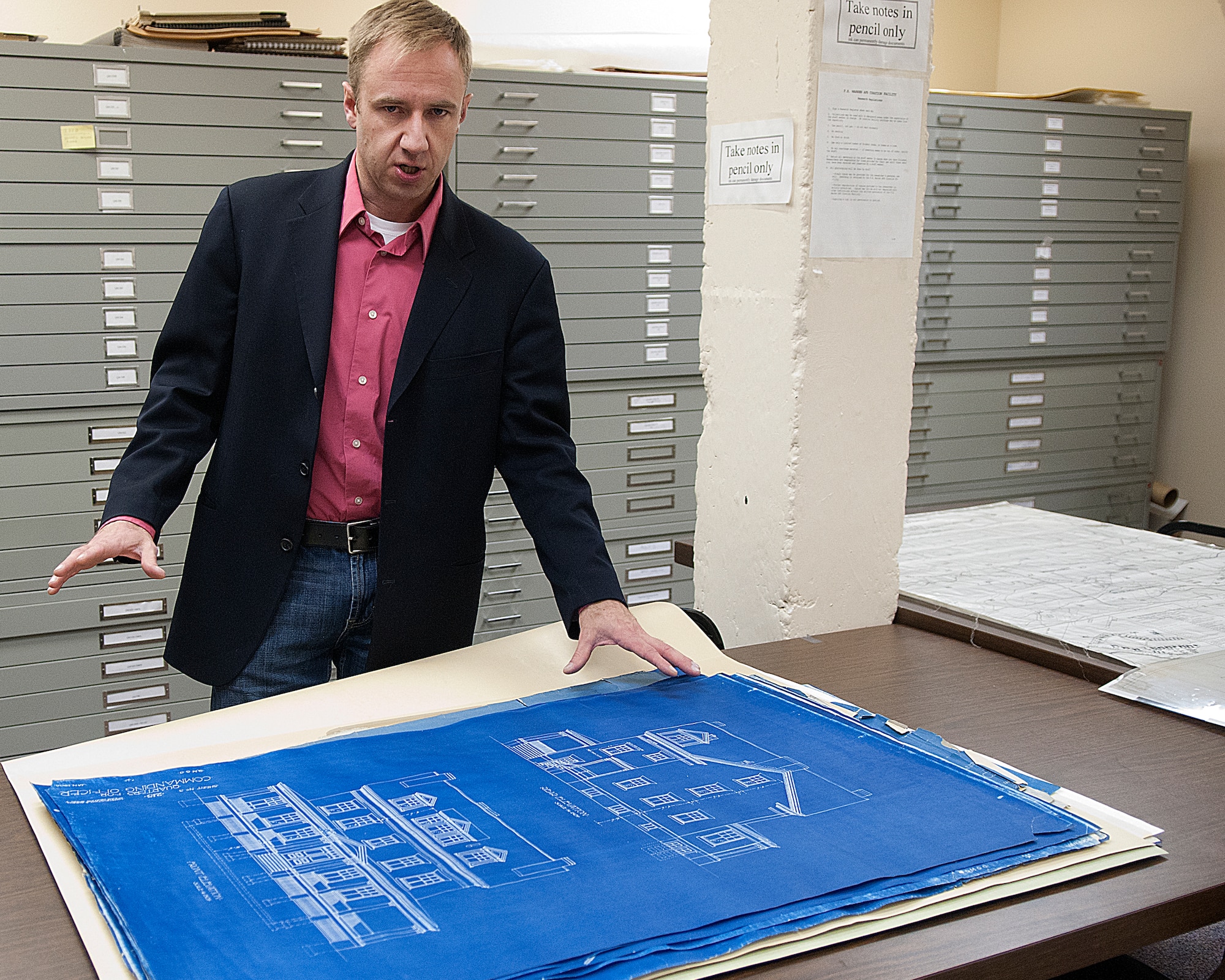 Travis Beckwith, 90th Civil Engineer Squadron cultural resources manager, in the document vault of the F. E. Warren curation facility known as “the bunker” stores blueprints dating back to 1908 March 27. Signs on the pillar next to Beckwith warn visitors to the vault to take notes in pencils only. “We are an archive.” Beckwith said. “Technically we are open to the public. We’ve got folks who come here every once in a while to do research.” (U.S. Air Force photo by R.J. Oriez)
