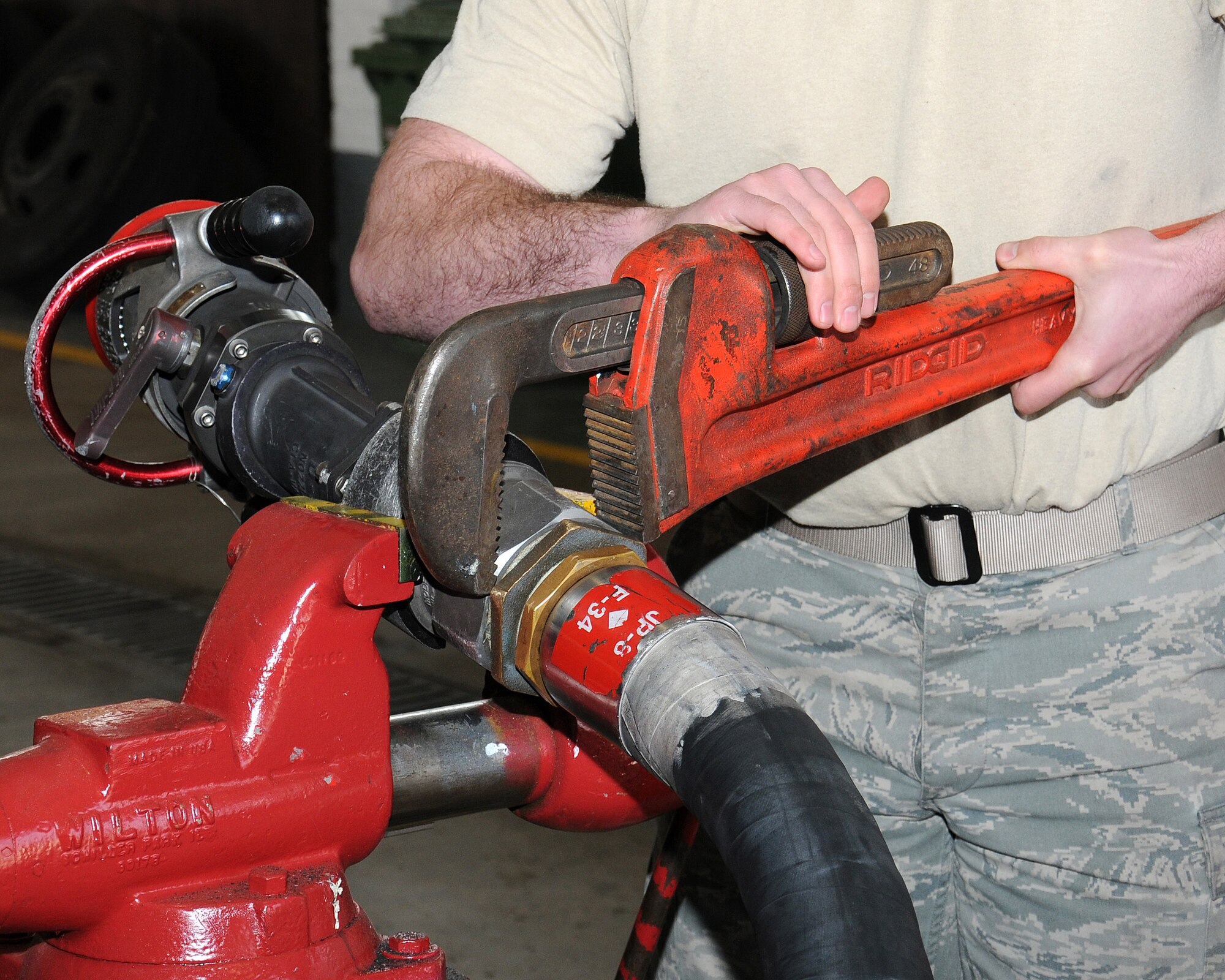 Senior Airman Aaron Smith, 100th Logistics Readiness Squadron refueling maintenance technician from Anacoco, La., repairs a refueling hose using a pipe wrench April 10, 2013, at RAF Mildenhall, England. This equipment is mission essential so it must be carefully maintained in order to keep planes in the air. (U.S. Air Force photo by Gina Randall/Released)