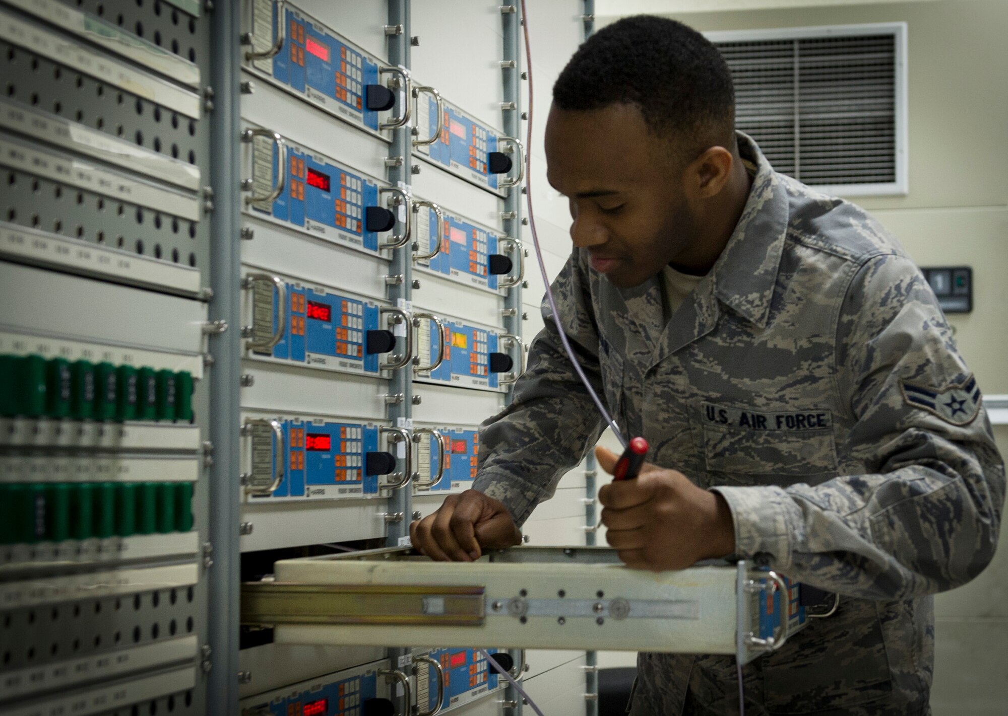 YOKOTA AIR BASE, Japan -- Airman 1st Class Willie McNair Jr., 374th Communications Squadron RF transmission systems apprentice, works on equipment inside the satellite operations room at Camp Zama, Japan, April 9, 2013. The satellite equipment floor contains all the associated instruments feeding into the satellite dish. Proper maintenance of this equipment is important to ensure no interruption of service throughout the Pacific region. (U.S. Air Force photo by Senior Airman Andrea Salazar)