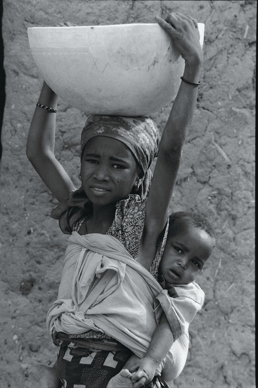 Throughout the region one sees young girls like this one carrying large containers of water on their heads as they carry a baby sister or brother on their back.  This girl is about nine years old.  She has never attended school.