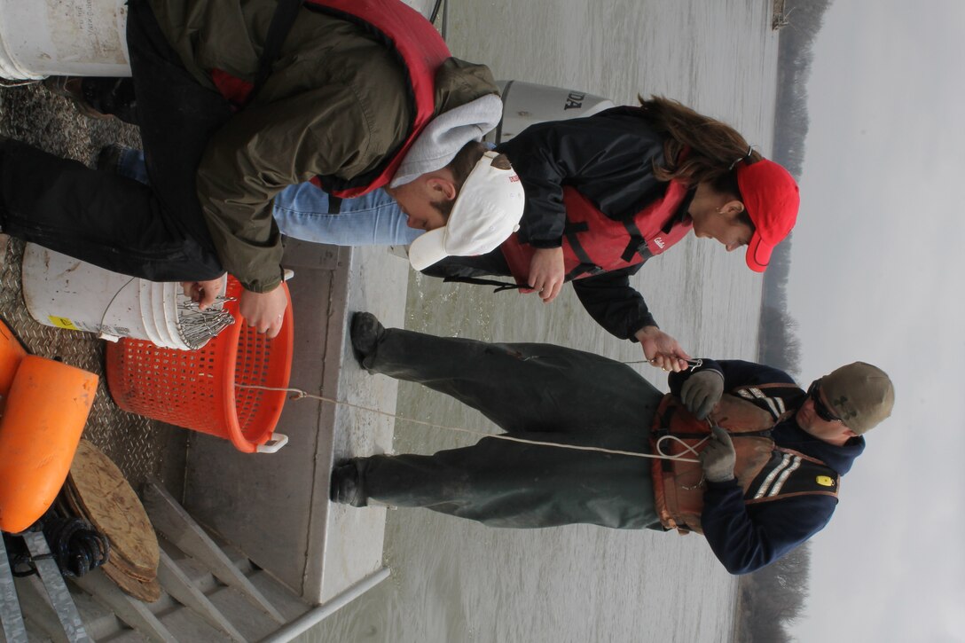 Omaha District Leadership Development Program participant and Engineer in the Hydrologic Engineering Branch, Josh Melliger hands LDP participant and Public Affairs Specialist, Eileen Williamson baited hooks to be clipped to trotlines as they are placed in the Missouri River during pallid sturgeon broodstock collection efforts with the Nebraska Game and Parks Commission, April 8.