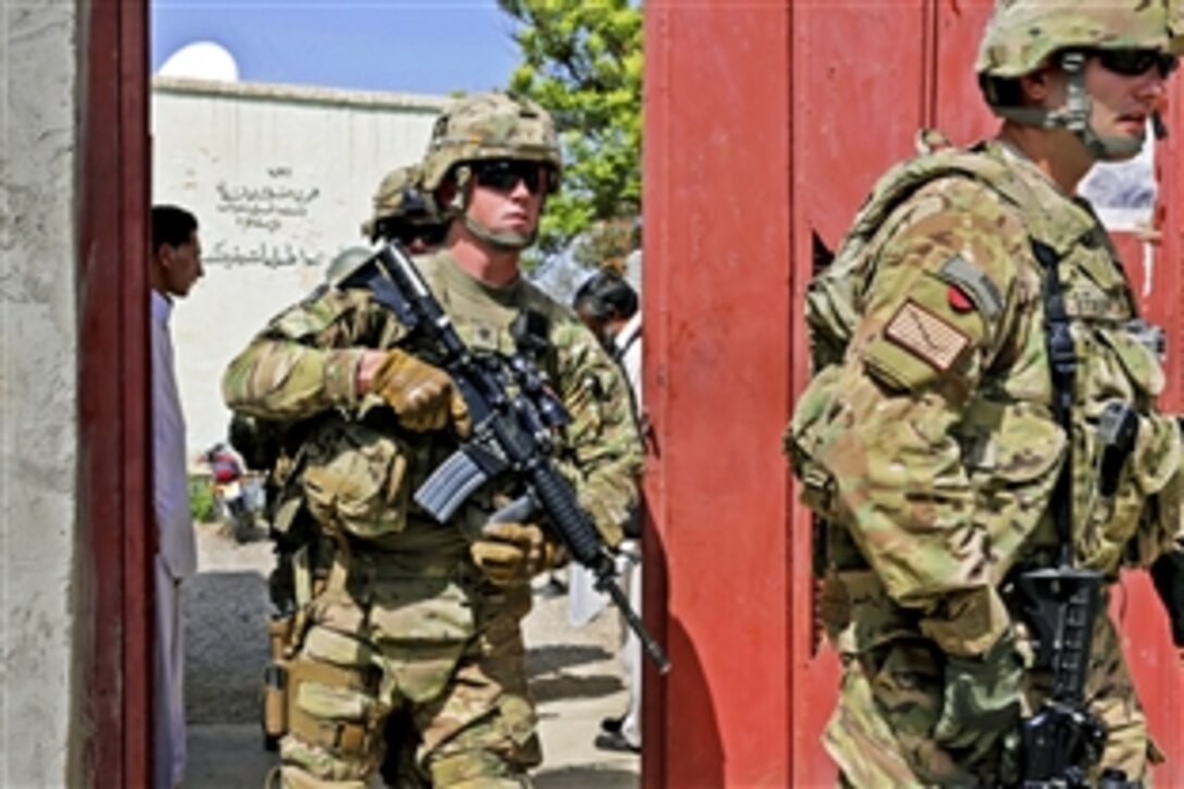 U.S. Army Spc. Thaxal Potter, left, provides security as U.S. Navy Lt. j.g. Matthew Stroup, right, and other troops depart the directorate of information and culture offices following a meeting in Farah City, Afghanistan, April 10, 2013. Stroup, a public affairs officer, and Potter are assigned to Provincial Reconstruction Team Farah.