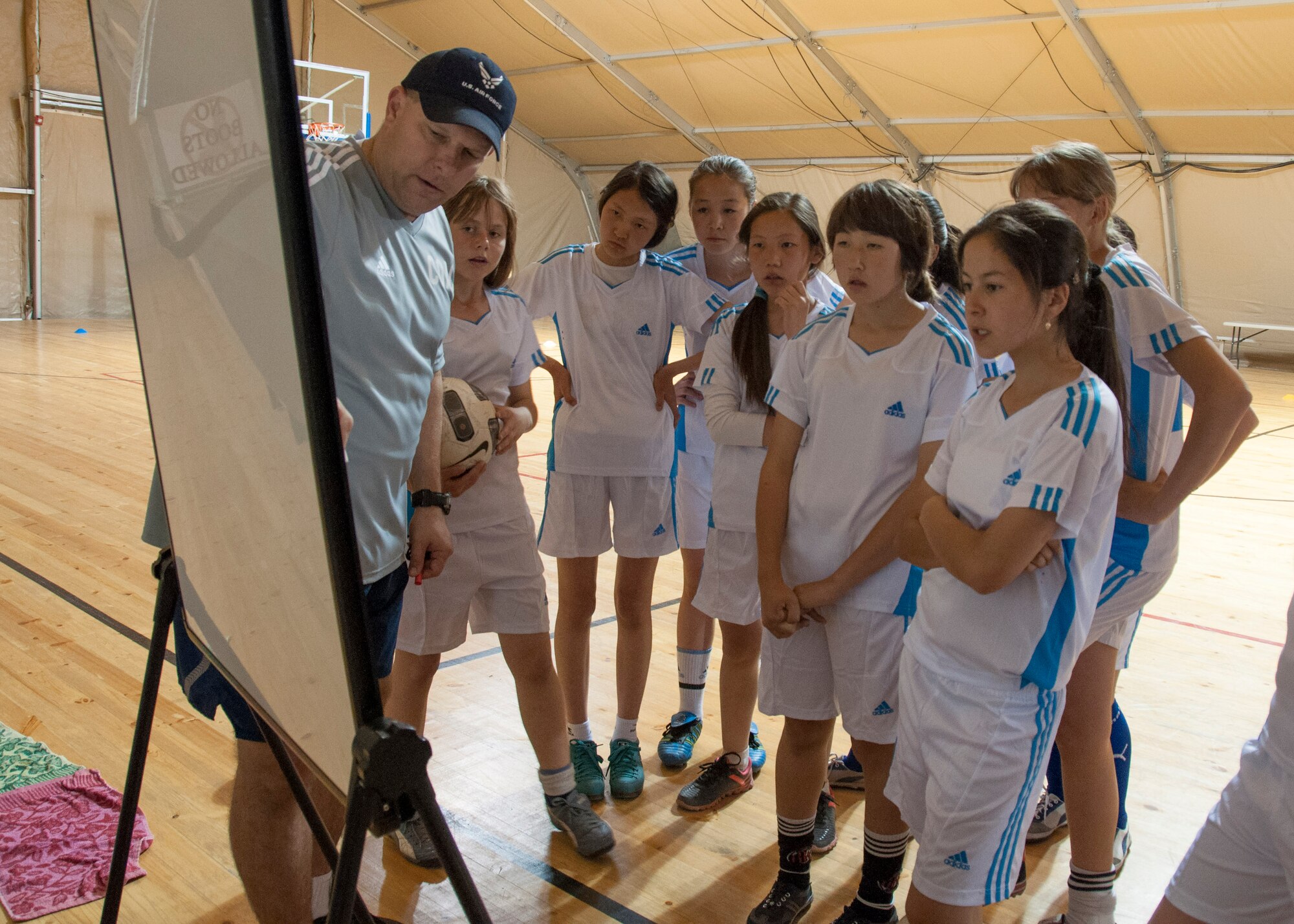 Col. Robert Mallets, 376th Air Expeditionary Wing vice commander and coach of the Liberando Football Club, uses a diagram to explain a soccer drill to a group of Kyrgyz girls April 11, 2013, at Transit Center at Manas, Kyrgyzstan. The girls practiced dribbling, passing and shooting with soccer players from the Transit Center. (U.S. Air Force photo/Tech. Sgt. Rachel Martinez)