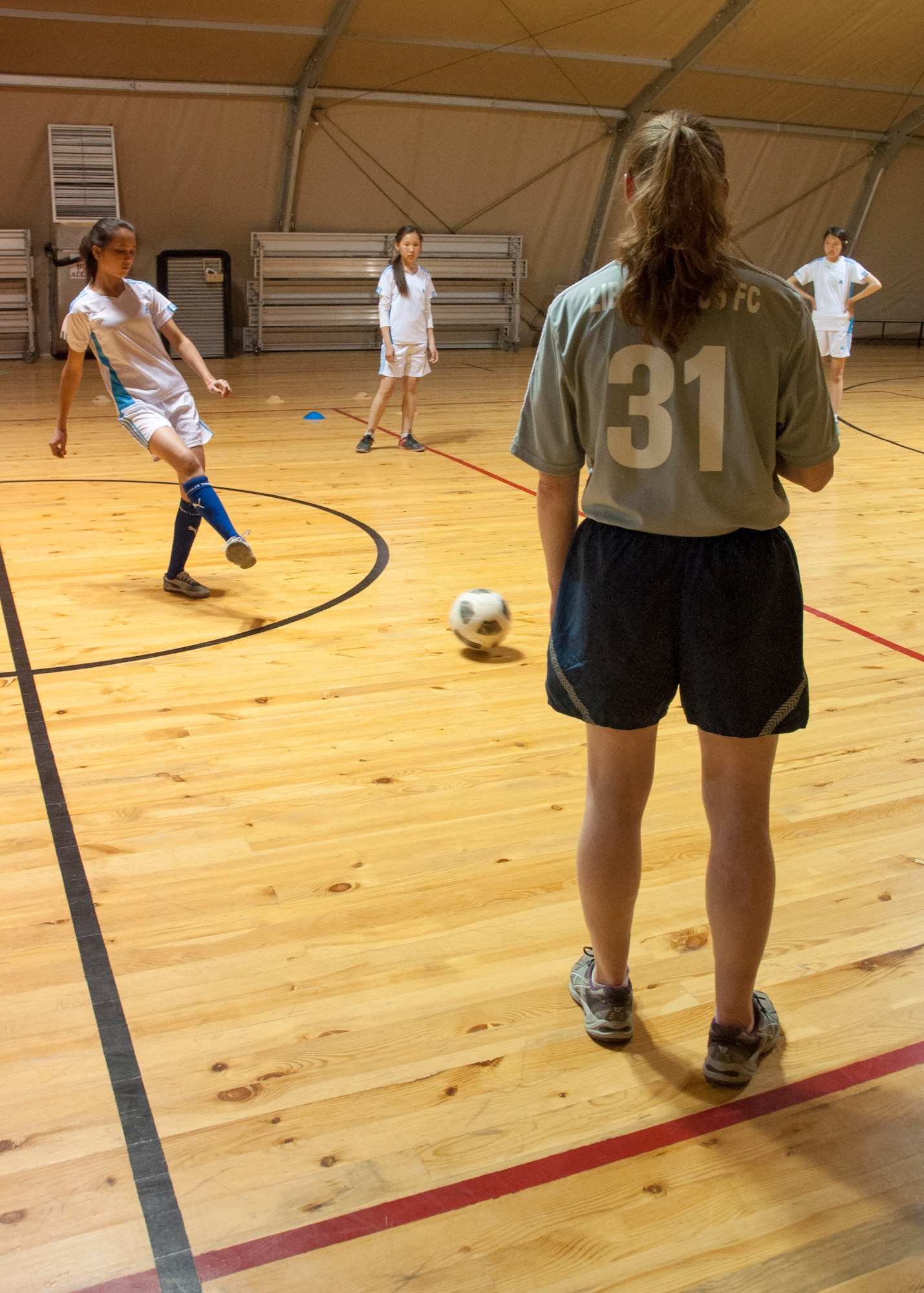 Senior Airman Caroline Copenhaver, wearing the number 31, practices passing skills with a group of Kyrgyz girls April 11, 2013, at Transit Center at Manas, Kyrgyzstan. The girls visited the Transit Center for a tour and exposure to America-style soccer skills. (U.S. Air Force photo/Tech. Sgt. Rachel Martinez)