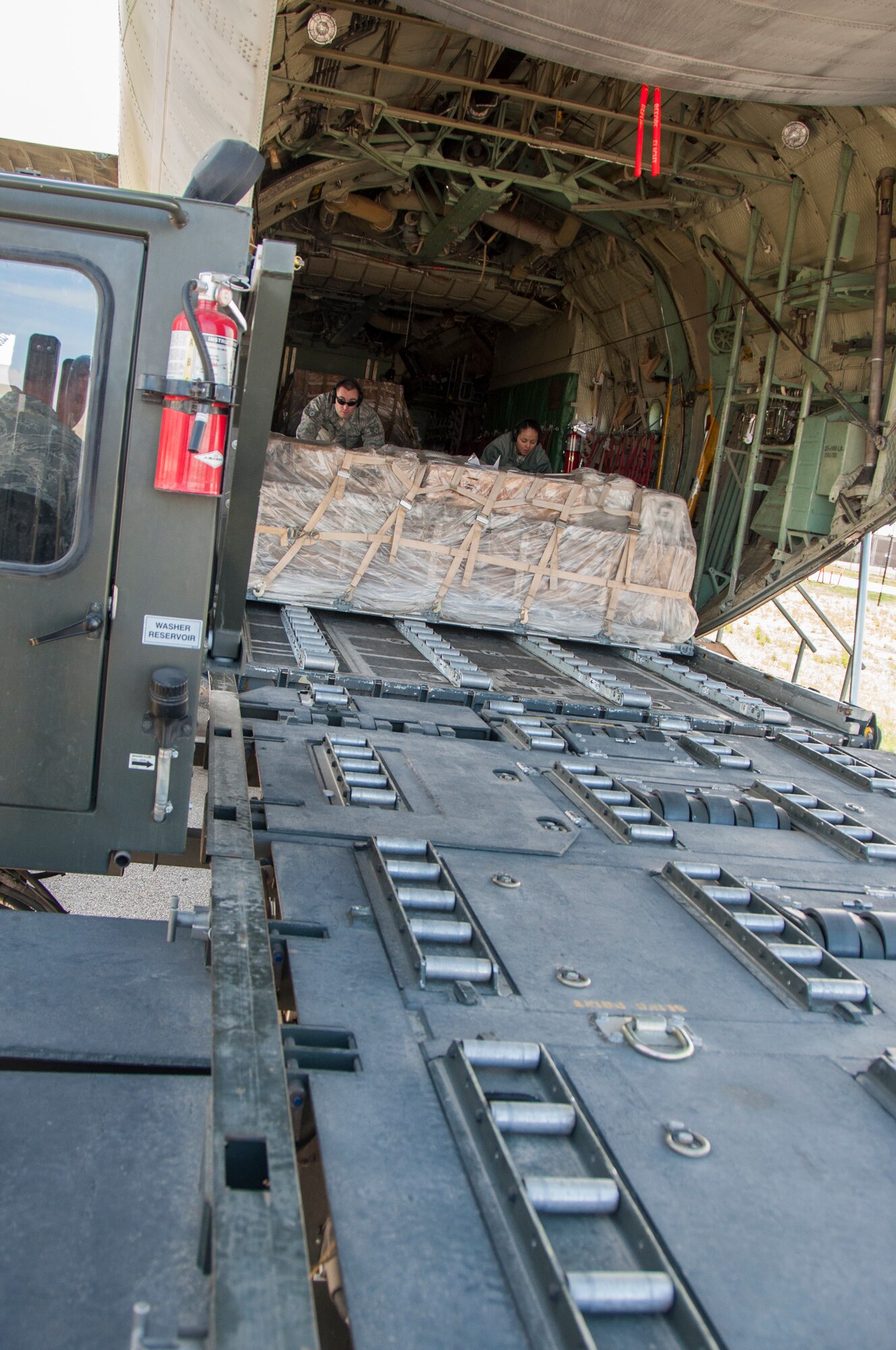 Staff Sgt. Kevin Erskine, 67th Aerial Port Squadron air transportation specialist, and Airman Amanda Cervantes, 67th APS journeyman, unload cargo from a training C-130 onto a loading truck. The truck has rollers on the bed designed to make it easier to move cargo to and from the truck. (U.S. Air Force photo/Senior Airman Crystal Charriere)