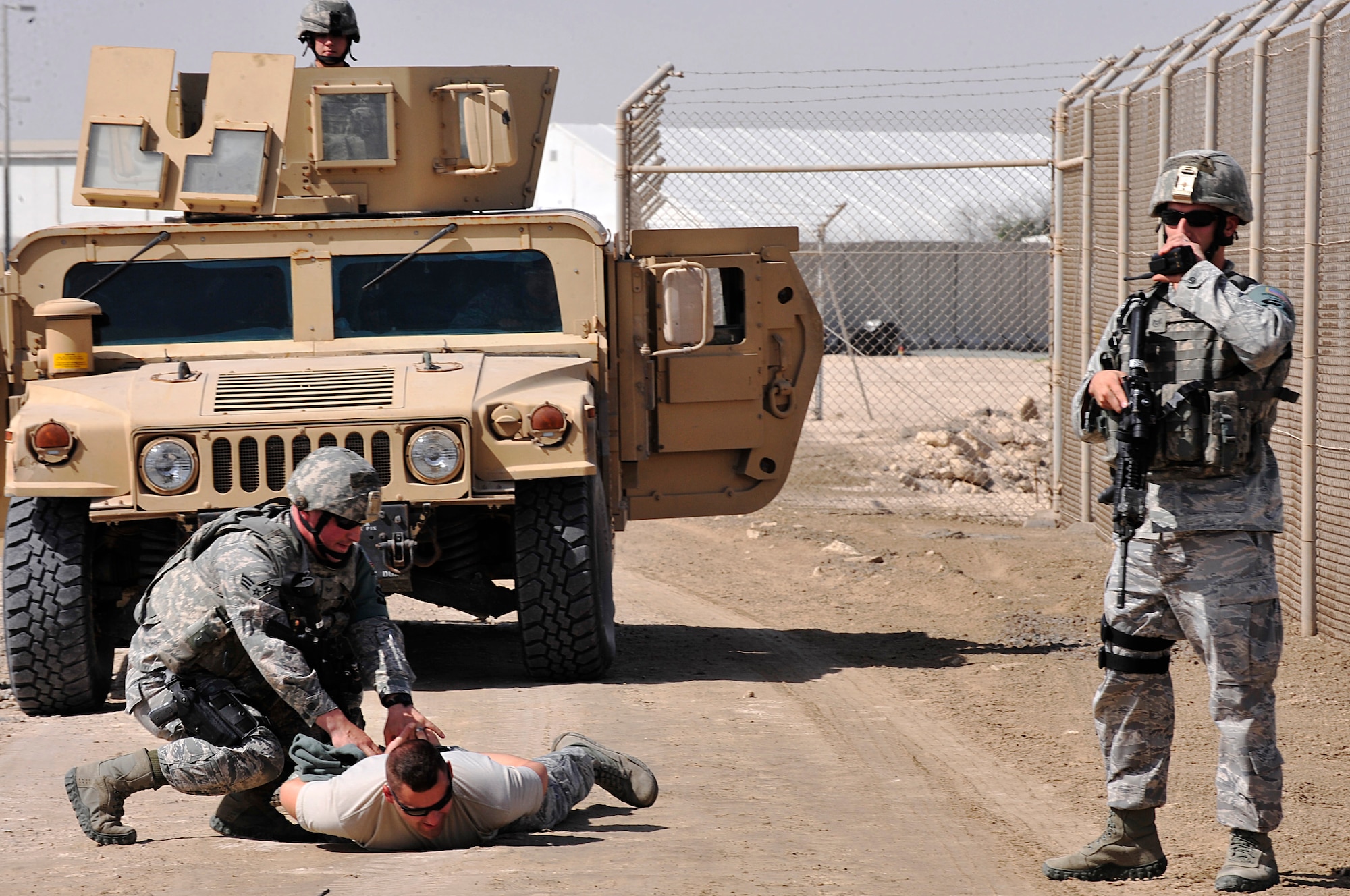 Members of the 380th Expeditionary Security Forces Squadron apprehend an intruder, played by Airman 1st Class William Densford, 380th ESFS random access measures team member, attempting to infiltrate the installation during a demonstration of the Tactical Automated Security System (TASS) at an undisclosed location in Southwest Asia Mar. 20, 2013. TASS, installed at bases throughout the area of responsibility, alleviates the need for constant foot patrols performed by SFS personnel, which frees them to focus their attention on more vulnerable locations and increases the overall security of the installation. (U.S. Air Force photo by Tech. Sgt. Christina M. Styer/Released)  