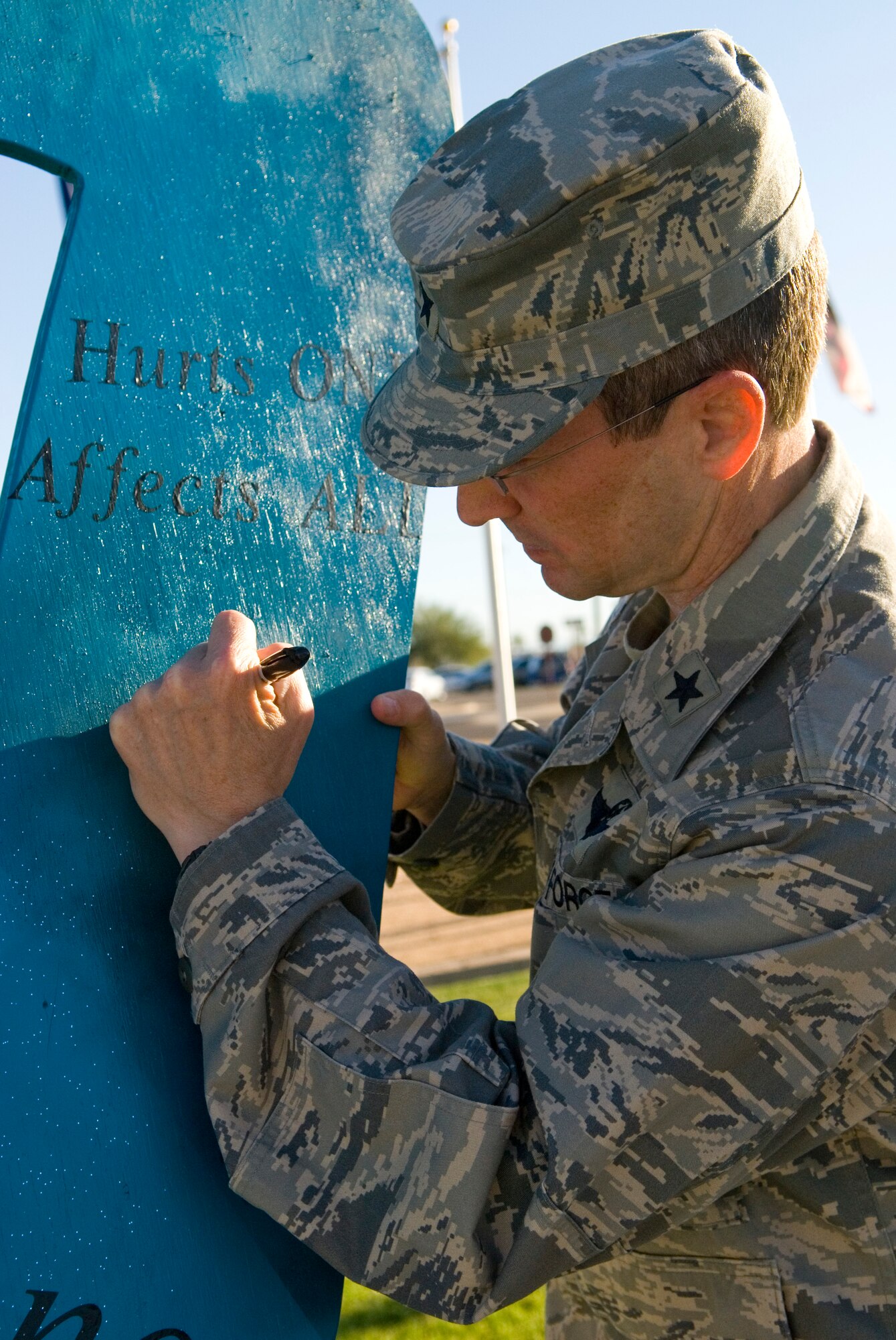 Brig. Gen. Mike Rothstein, 56th Fighter Wing commander, signs the Sexual Assault Awareness Month ribbon during an opening ceremony in Flag Park April 3 at Luke Air Force Base. The theme for this year’s awareness month is “We own it. We’ll solve it … Together.” The commander encouraged supervisors and leaders to understand the problem and help deter sexual assault from happening within the ranks. (U.S. Air Force photo/Staff Sgt. Nestor Cruz)