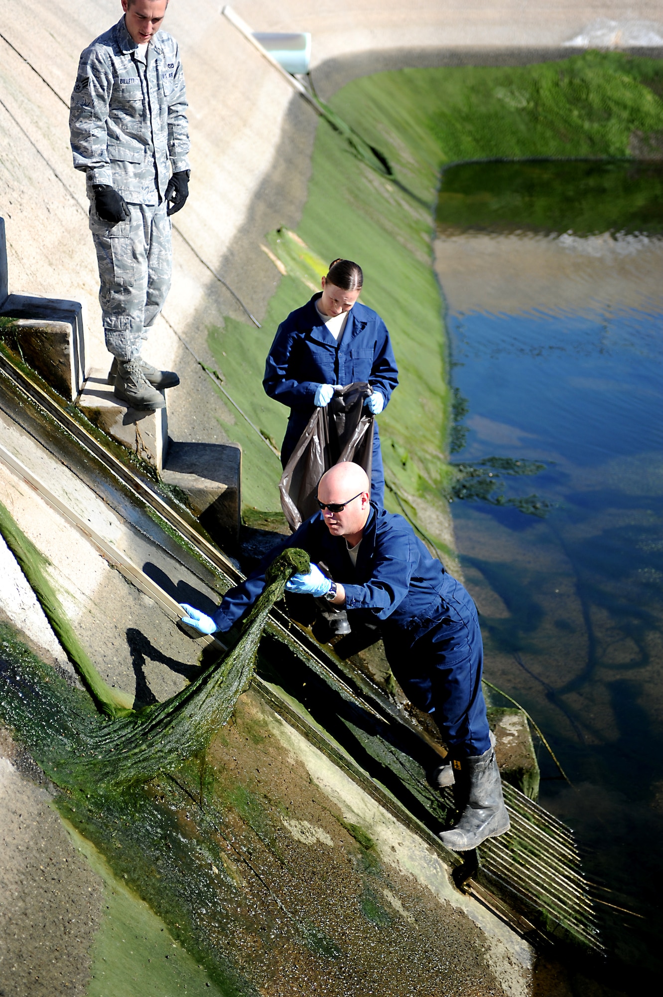 Chief Master Sgt. David Staton, 56th Fighter Wing command chief, pulls moss from the wall of the final treatment pond at the Luke Air Force Base waste water treatment facility. By the time the water arrives to this point it has been cleaned so well that fish can live in the pond and the water is used to irrigate the golf course. (U.S. Air Force photo/Staff Sgt. C.J. Hatch)