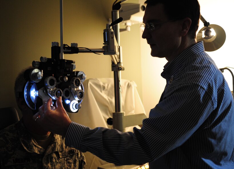 Dr. Allan Rhoads, 92nd Medical Group optometrist, uses a phropter to check a patient's vision with different lenses to determine his eyeglass prescription at Fairchild Air Force Base, Wash., April 11, 2013. Retirees and their dependents are authorized one routine eye exam to include refraction for glasses every two years. (U.S. Air Force photo by Airman 1st Class Janelle Patiño)