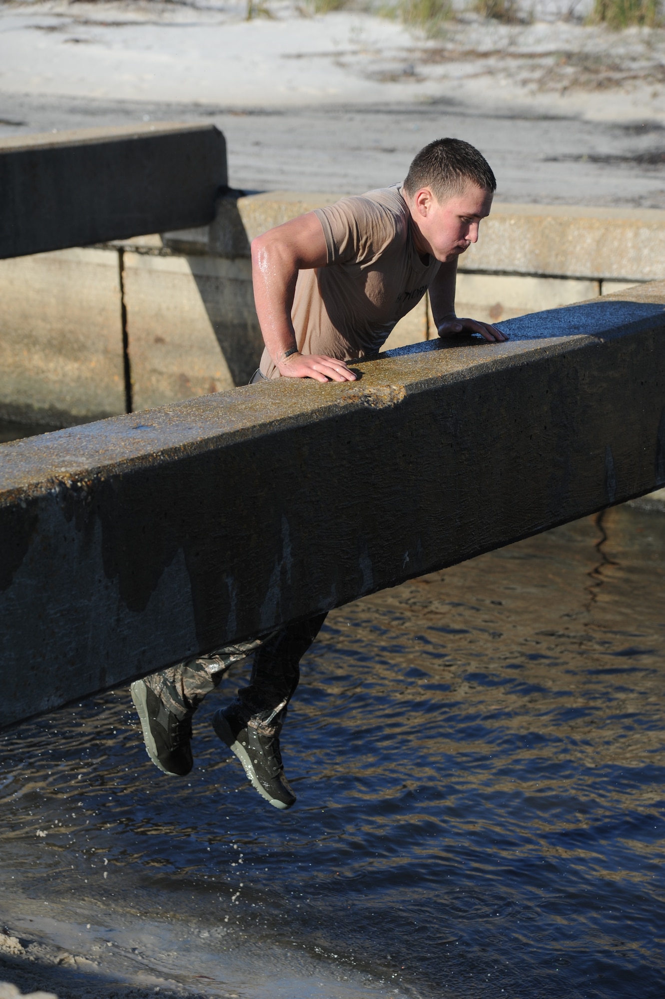 Airman 1st Class Jordan Hathorn, 334th Training Squadron, pulls himself onto a cement pillar during the combat controllers’ physical training session April 12, 2013, on Biloxi beach.  Combat controllers are ground troops who are embedded with special forces teams and provide close-air support for special forces units. While at Keesler, trainees learn how to run, swim, carry a rucksack and conduct air traffic control. These Airmen are prepared physically and mentally for the demands of the combat controller pipeline while earning air traffic control certification in just 15 weeks.  (U.S. Air Force photo by Kemberly Groue)