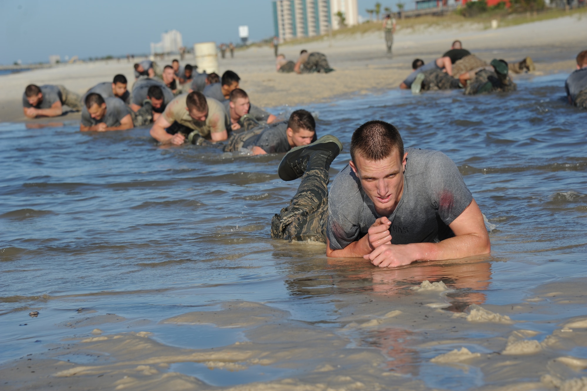 Airman 1st Class Blake Richards, 334th Training Squadron, drags his way through a 100-meter low crawl in a puddle of water during the combat controllers’ physical training session April 12, 2013, on Biloxi beach.  Combat controllers are ground troops who are embedded with special forces teams and provide close-air support for special forces units. While at Keesler, trainees learn how to run, swim, carry a rucksack and conduct air traffic control. These Airmen are prepared physically and mentally for the demands of the combat controller pipeline while earning air traffic control certification in just 15 weeks.  (U.S. Air Force photo by Kemberly Groue)