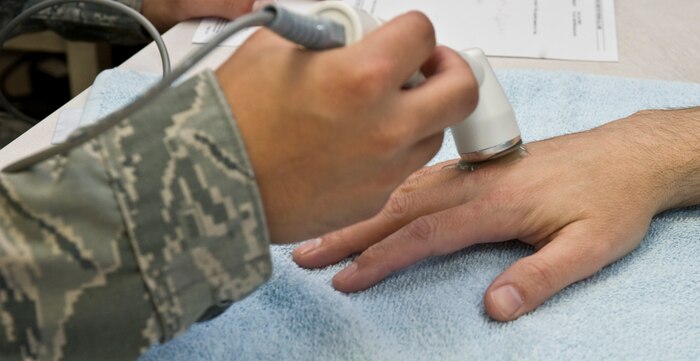 Senior Airman Juan Arciniegas, 99th Medical Operations Squadron occupational therapy technician, performs an ultra sound on James Looman's, 57th Wing information assurance officer, right hand April 3, 2013, at Nellis Air Force Base, Nev. A function of occupational therapy clinic is to help patients recover from fractures, cumulative trauma syndromes, tendon injuries, nerve entrapment, and post-surgical rehabilitation within someone's upper body extremities. (U.S. Air Force photo by Senior Airman Matthew Lancaster)
