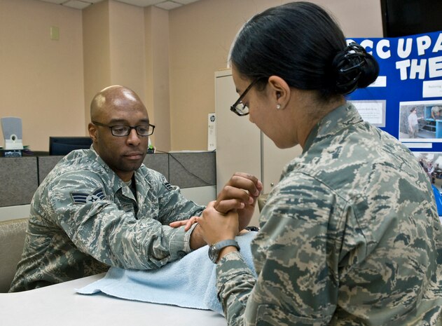 1st Lt. Matilda Brunner, 99th Medical Operations Squadron occupational therapist, and Senior Airman Darryl Wilson, 99 MDOS physical therapy technician, demonstrate a stretching exercise April 3, 2013, at Nellis Air Force Base, Nev. This stretching exercise is meant to rehabilitate the movement in the wrist and hand. (U.S. Air Force photo by Senior Airman Matthew Lancaster)